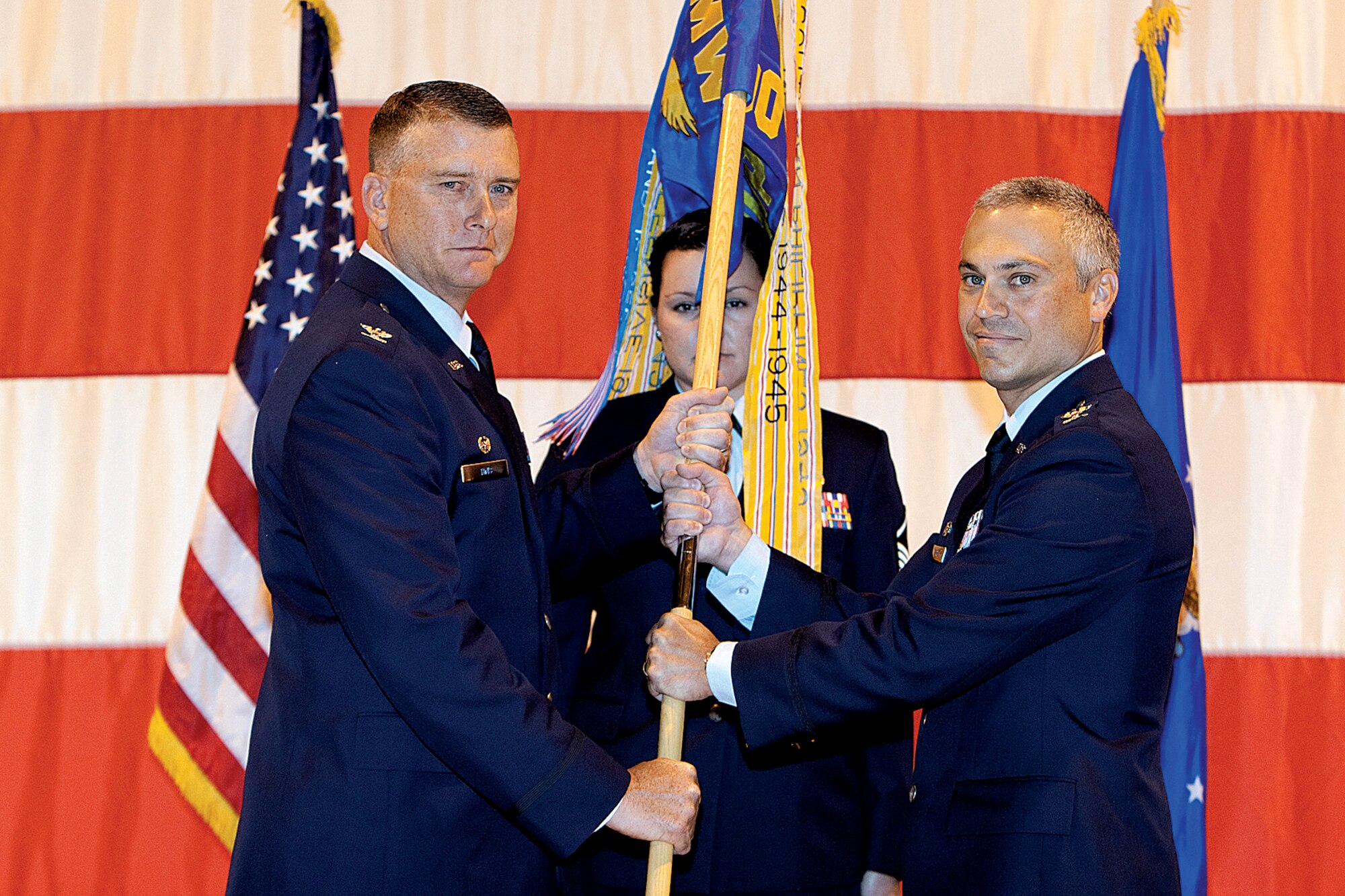 Col. Robert Vercher assumes command of the 90th Operations Group from Col. Bryant Anderson on July 8. Col. Greg Tims, 90th Missile Wing commander, presents Colonel Vercher with the 90th OG guideon. (U.S. Air Force photo by Jeff Allred)