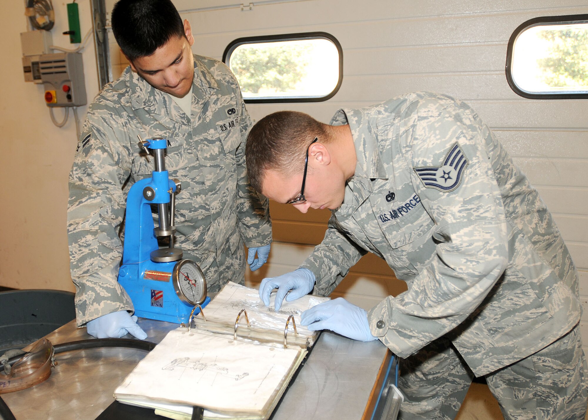 Staff Sgt. Joshua Walters, 31st Maintenance Squadron hydraulics craftsman, shows Airman 1st Class Alexander Vergara, 31st MXS hydraulics journeyman, the training ordinance on connecting a torque link to an F-16 Fighting Falcon nose landing gear shock strut July 14 at the hydraulics back shop.  When a hydraulic part malfunctions, the team inspects, tears down, repairs, rebuilds and cleans the part.  (U.S. Air Force photo/Senior Airman Tabitha M. Lee)