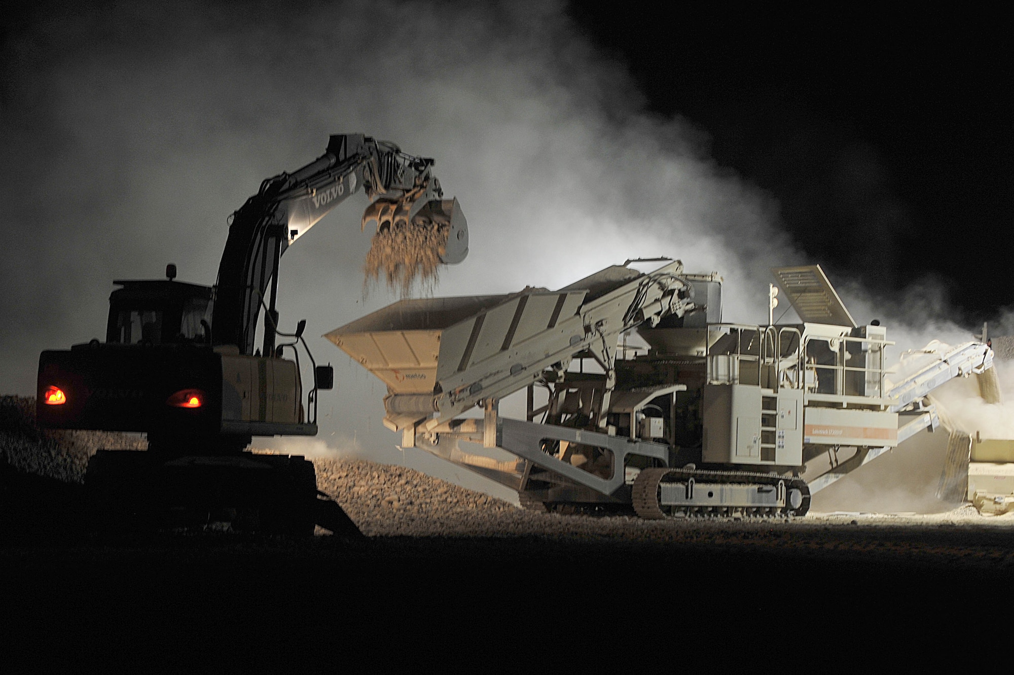 An excavator dumps rocks onto a conveyer belt to be crushed to make cement for a runway at Camp Dwyer, Afghanistan June 24, 2010.  The runway will be used to accommodate heavier aircraft.  (U.S. Air Force photo/Staff Sgt. Quinton Russ/released)