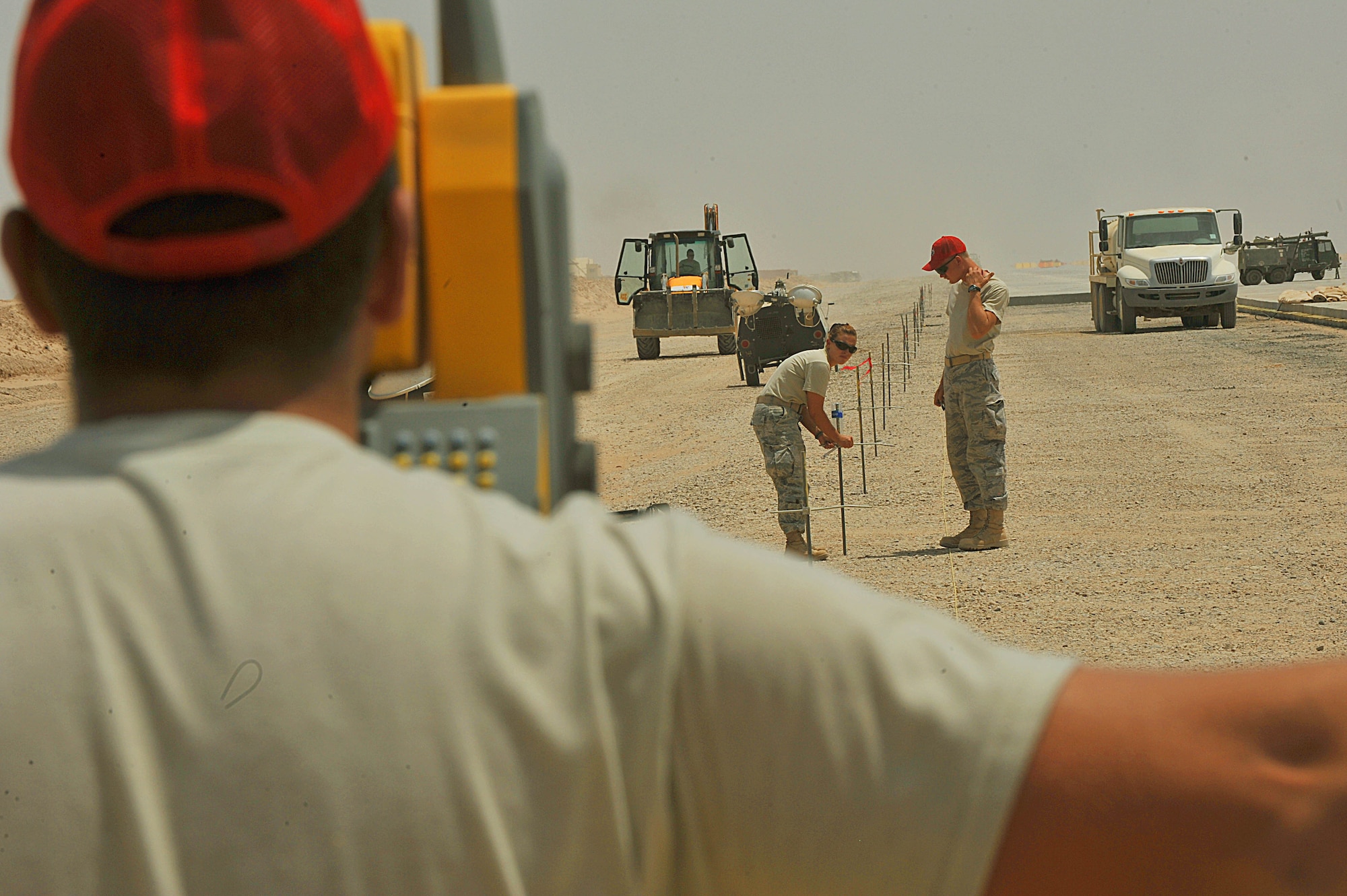 U.S. Air Force Tech. Sgt. Kevin Devore, foreground, gives corrections to Tech. Sgt. Rebecca Walsh, left, and Senior Airman Joseph Carbary during an alignment survey on an unfinished runway at Camp Dwyer, Afghanistan, June 25, 2010.  The runway will be used to accommodate heavier aircraft at Camp Dwyer.  The Airmen are engineers deployed 809th Expeditionary Red Horse Squadron.  (U.S. Air Force photo/Staff Sgt. Quinton Russ/released)