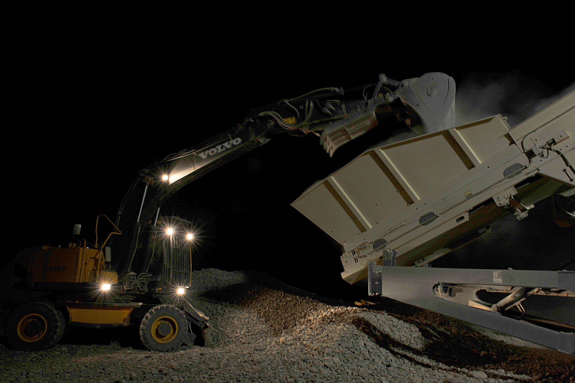 An excavator dumps rocks onto a conveyer belt to be crushed to make cement for a runway at Camp Dwyer, Afghanistan, June 24, 2010.  The runway will be used to accommodate heavier at Camp Dwyer. (U.S. Air Force photo/Staff Sgt. Quinton Russ/released)