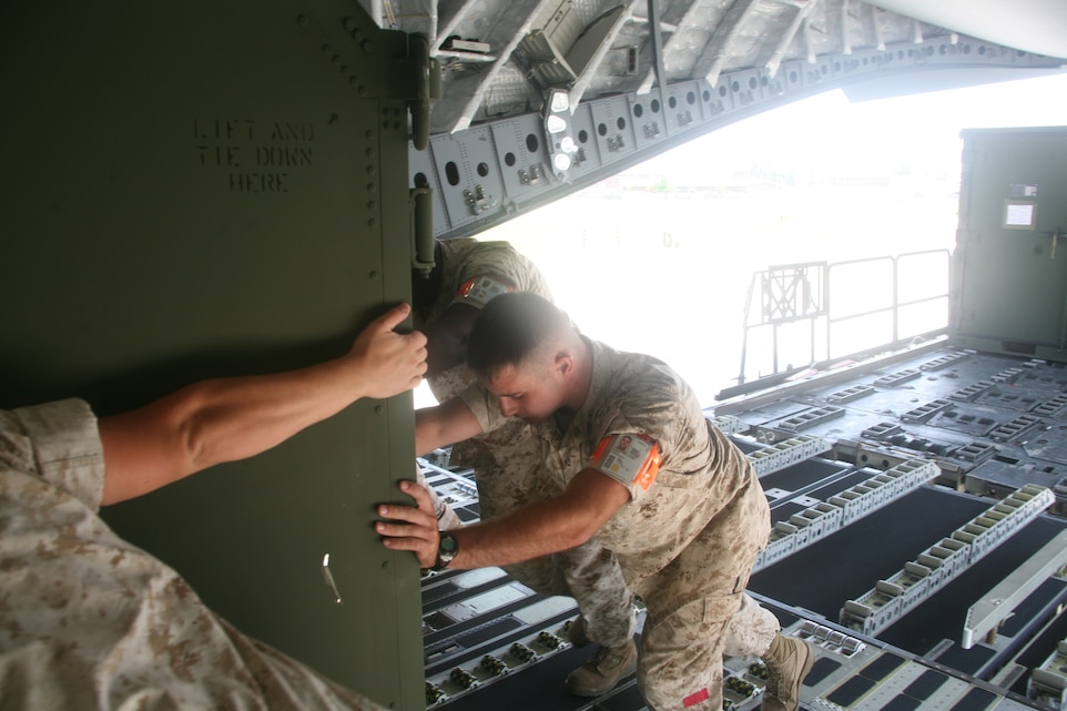 Aerial Port of Embarkation Marines push a storage unit onto an Air Force Lockheed C-130J “Super” Hercules aboard Cherry Point. “Almost every East Coast Marine who deploys goes through the APOE,” said Sgt. Darrell P. Cohn, the operations chief with Aerial Port Operations Group.