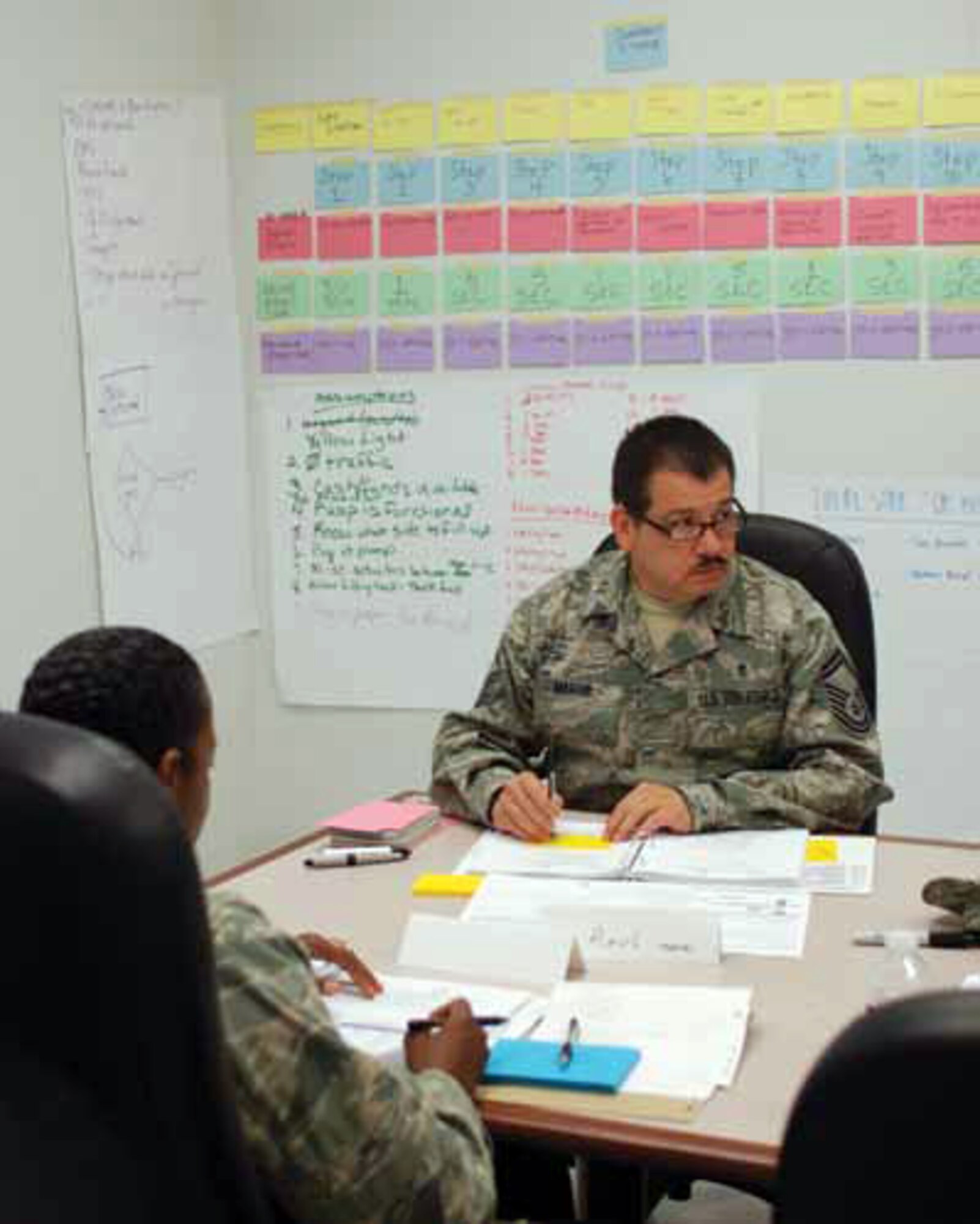 Senior Master Sgt. Raul Martir takes notes during a discussion at the Green Belt certification course, which was held at March ARB. In the background are note cards which illustrate value stream mapping which helps determine “value added” for customers.  (U.S. Air Force photo by Megan Just)
