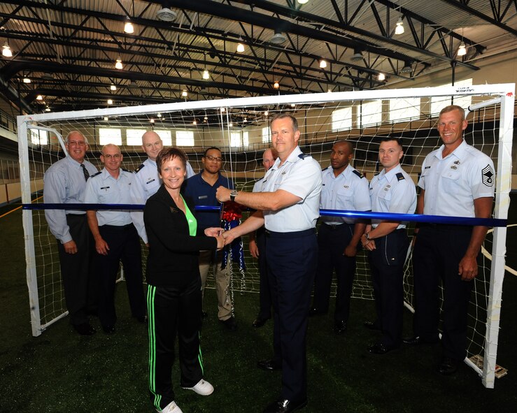 Col. Don Shaffer, 319th Air Refueling Wing commander, and Carol Muir, 319th Force Support Squadron fitness center director, cut a ribbon symbolizing the opening of the newly renovated field house while others look on July 19 at the Grand Forks Air Force Base Fitness Center. The field house now has an $83,686 artificial turf surface. An official ceremony, followed by a soccer tournament, will be held July 28. For more information, call (701) 747-3384. (U.S. Air Force photo by Tech. Sgt. Johnny L. Saldivar) 