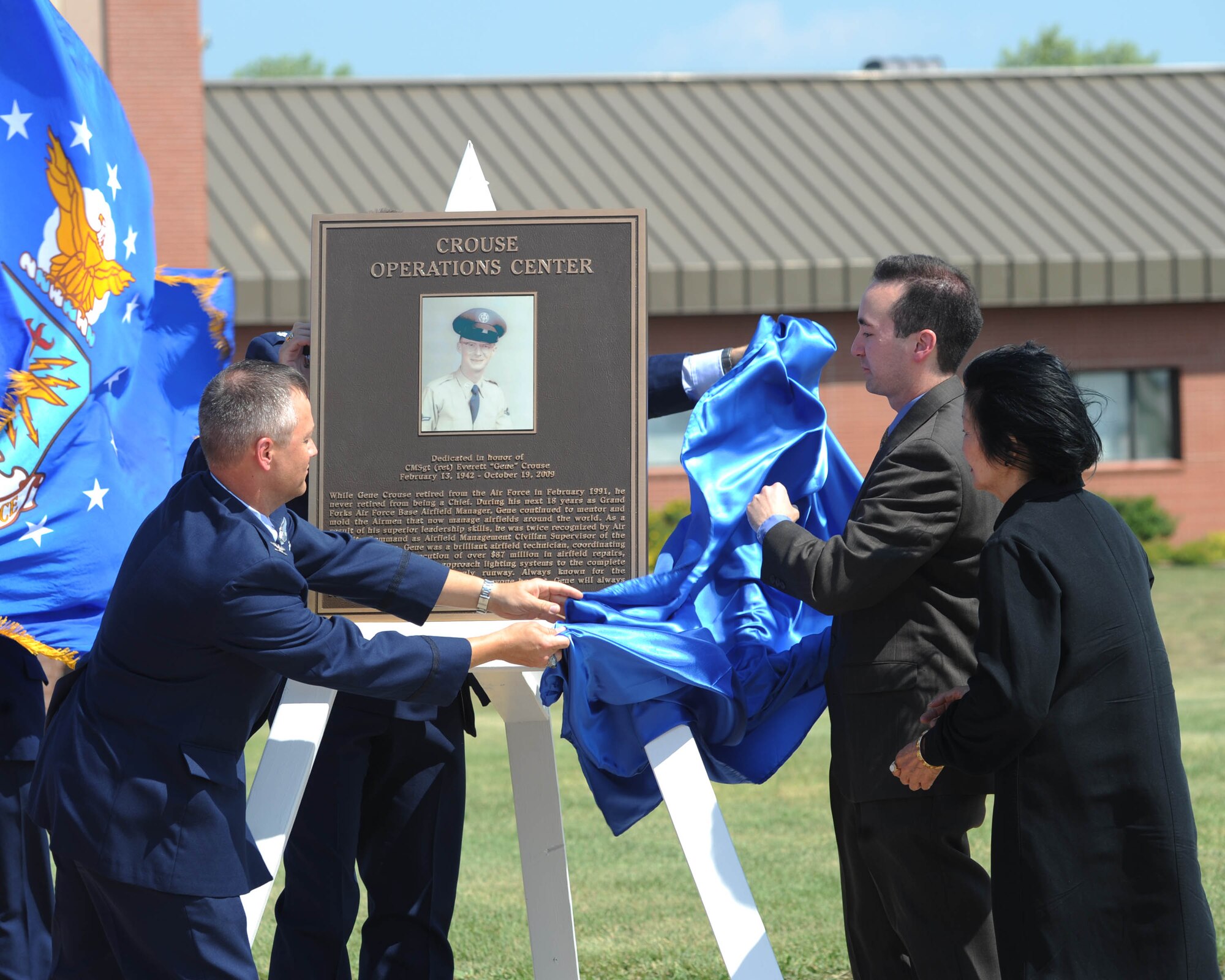 Base operations was renamed the Crouse Operations Center during a ceremony July 16 after retired Chief Master Sgt. and former Airfield Manager Everett “Gene” Crouse. The plaque to memorialize the building was unveiled by, from left to right, Col. Henry Polczer, 319th Operations Group commander, Lt. Col. Darin Driggers, 319th Operations Support Squadron commander, Bryan Crouse, son of Gene Crouse and Sun Cha Crouse, wife of Gene Crouse. (U.S. Air Force photo by Tech. Sgt. Johnny Saldivar) 