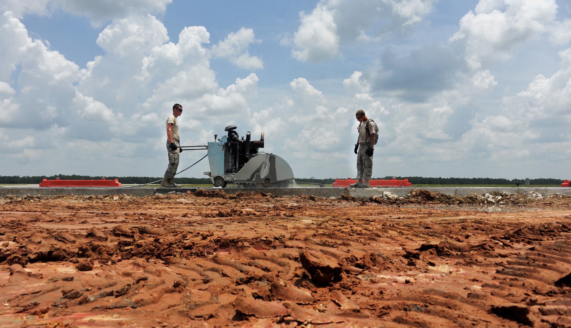 MOODY AIR FORCE BASE, Ga. -- Airmen 1st Classes Kendall Drake and Timothy Sackett, 823rd RED HORSE Squadron pavement equipment journeymen, from Hurlburt Field, Fla., use a concrete saw to cut into cement here July 15. The concrete saw has to cut through six inches of cement to make it to the soil on the airfield. (U.S. Air Force photo by Airman 1st Class Joshua Green/RELEASED)
