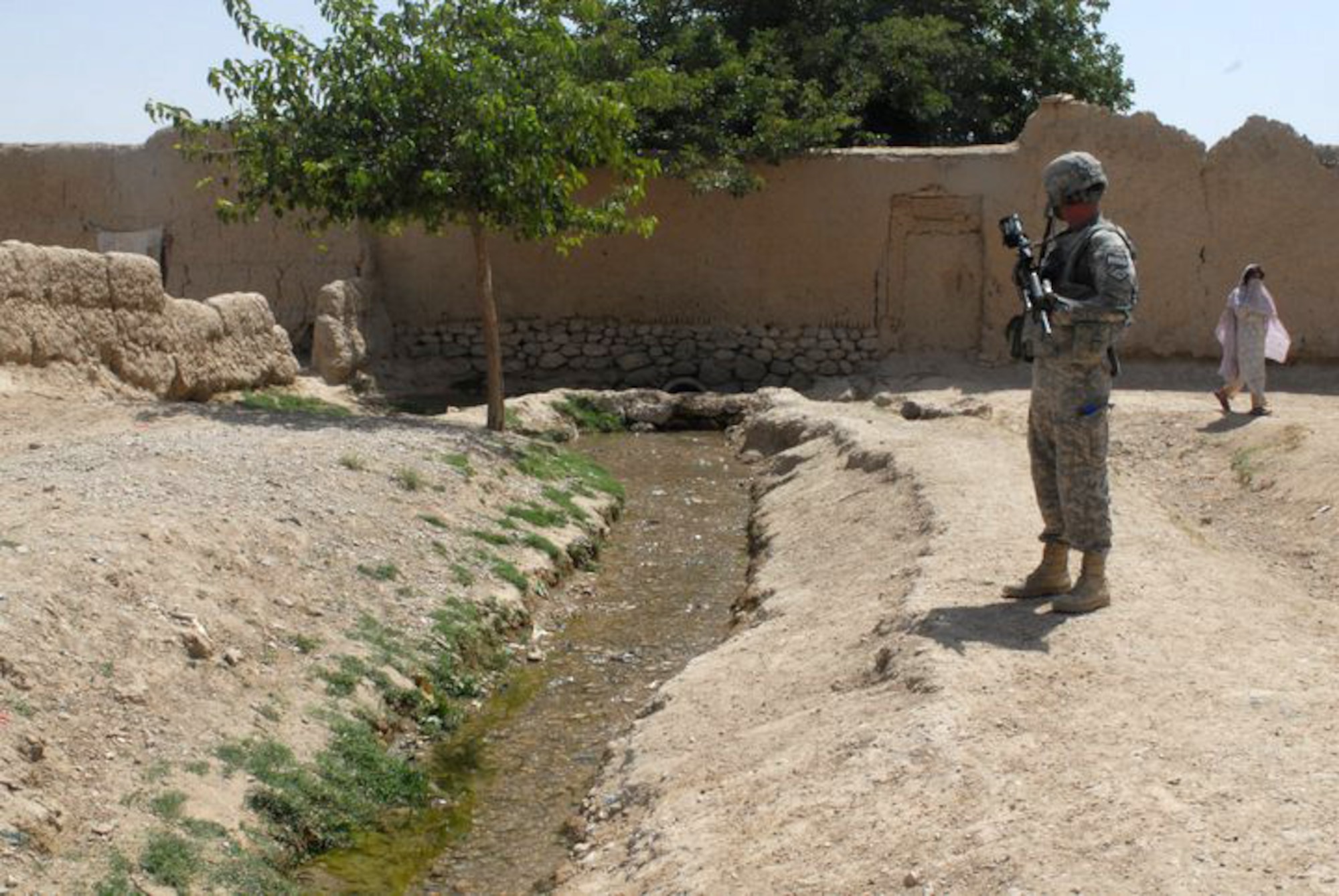 A member of the Arkansas National Guard's Agriculture Development Team observes a Karez stream flowing through a village near Qalat City, Afghanistan. Water is scarce in the high desert area of Zabul Province and the ADT Team is studying flow rate and water quality in villages around its forward operating base. The ADT is assisting the provincial irrigation director in formulating a plan to catch mountain runoff and reduce erosion, which fills Karezes and stops water flow. (Photo by Lt. Col. Keith Moore/ADT Public Affairs Officer)
