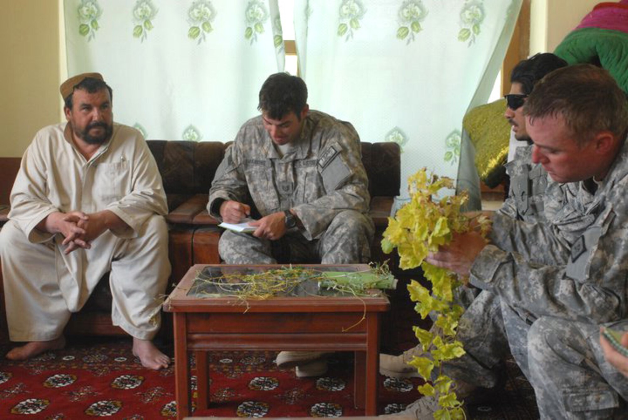 Tech Sgt. Justin Mankins takes notes during a discussion with a village elder near Qalat City, Afghanistan, while Sgt. 1st Class James Holm of Jonesboro examines a grape vine clipping for insect damage and nutrient deficiency. Mankins is one of three Airmen with the Arkansas Air National Guard's 188th Fighter Wing deployed with the Arkansas National Guard's Agriculture Development Team, which is currently deployed to southern Afghanistan. The team's focus is to expand and improve agriculture education, training and productivity. (Photo by Lt. Col. Keith Moore/ADT Public Affairs Officer)