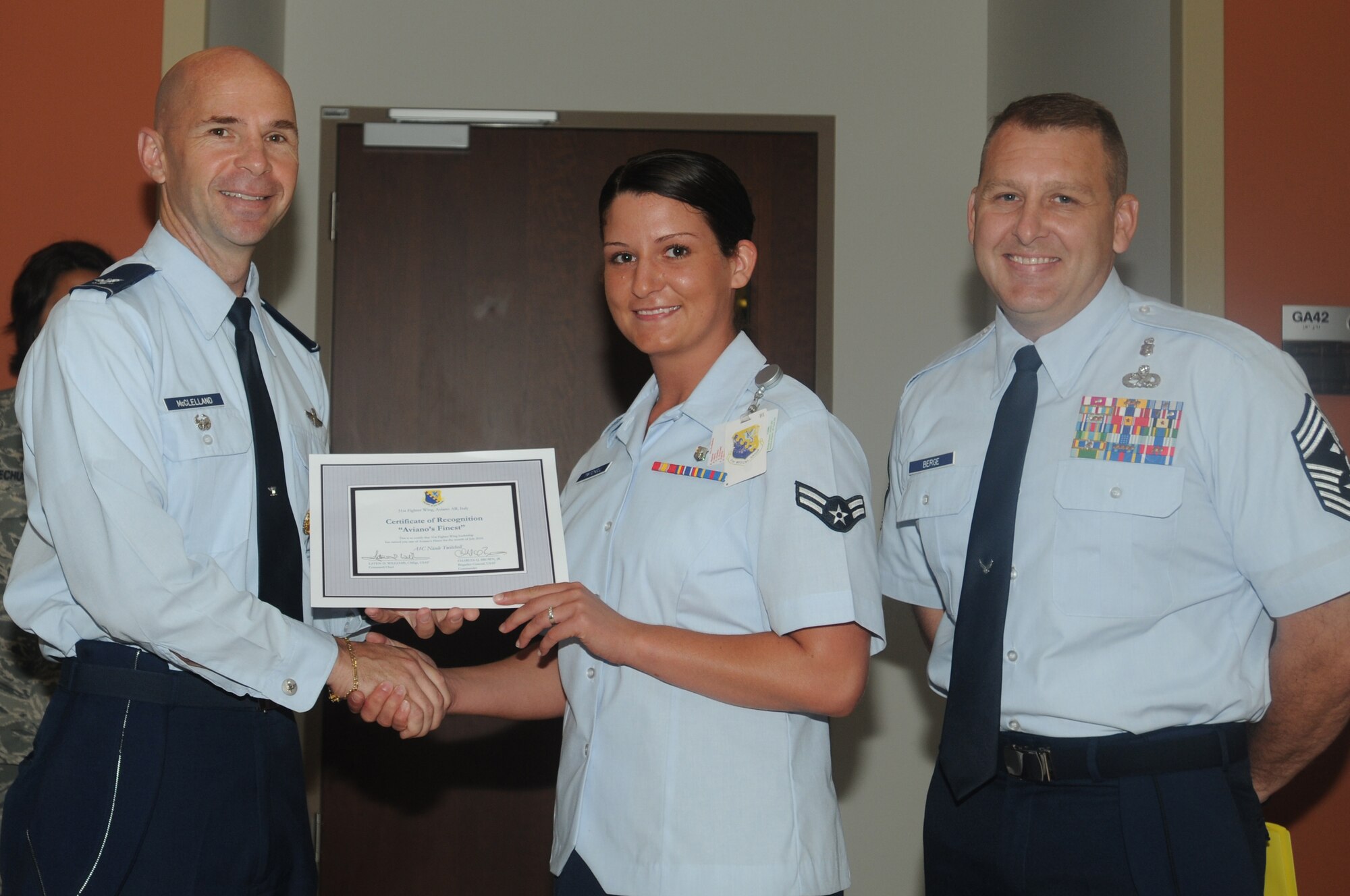 Col. Patrick A. McClelland (left), 31st Fighter Wing vice commander, along with Chief Master Sgt. Scott Berge (right), 31st Maintenance Squadron first sergeant, congratulate Airman First Class Nicole Twitchell, 31st Medical Operations Squadron medical records technician, on her selection as one of Aviano's Finest July 19. (U.S. Air Force photo/Airman LaVel Sterling)