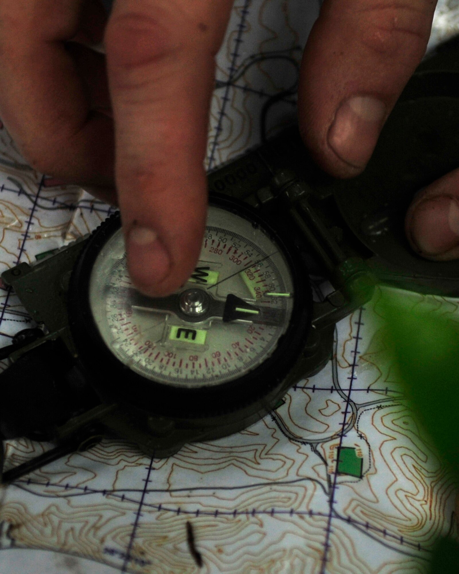 Staff Sgt. Justin Watters, Survival, Evade, Resistance and Escape specialist with the 353rd Operations Support Squadron, points out the coordinates and which way is North using a compass at Kadena Air Base’s Area 1  July 1. Every three years aircrew members must undergo a refresher course of SERE training. (U.S. Air Force photo by Senior Airman Amanda Grabiec)