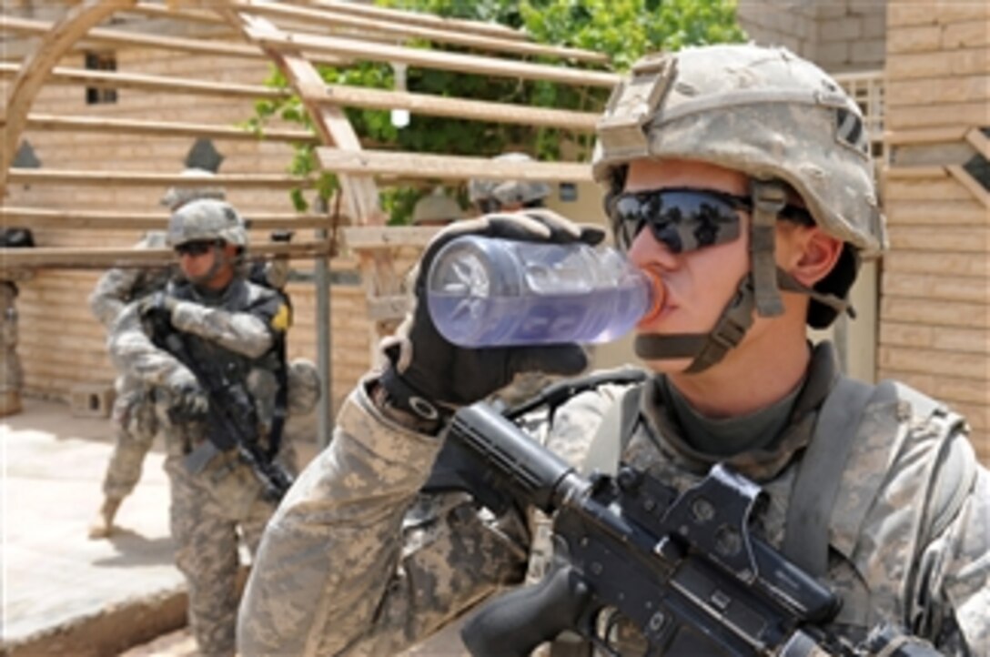 A U.S. Army soldier assigned to White Platoon, 1st Battalion, 30th Infantry Regiment, 2nd Brigade Combat Team, 3rd Infantry Division drinks water during a patrol in Rizgari, Iraq, on July 5, 2010.  