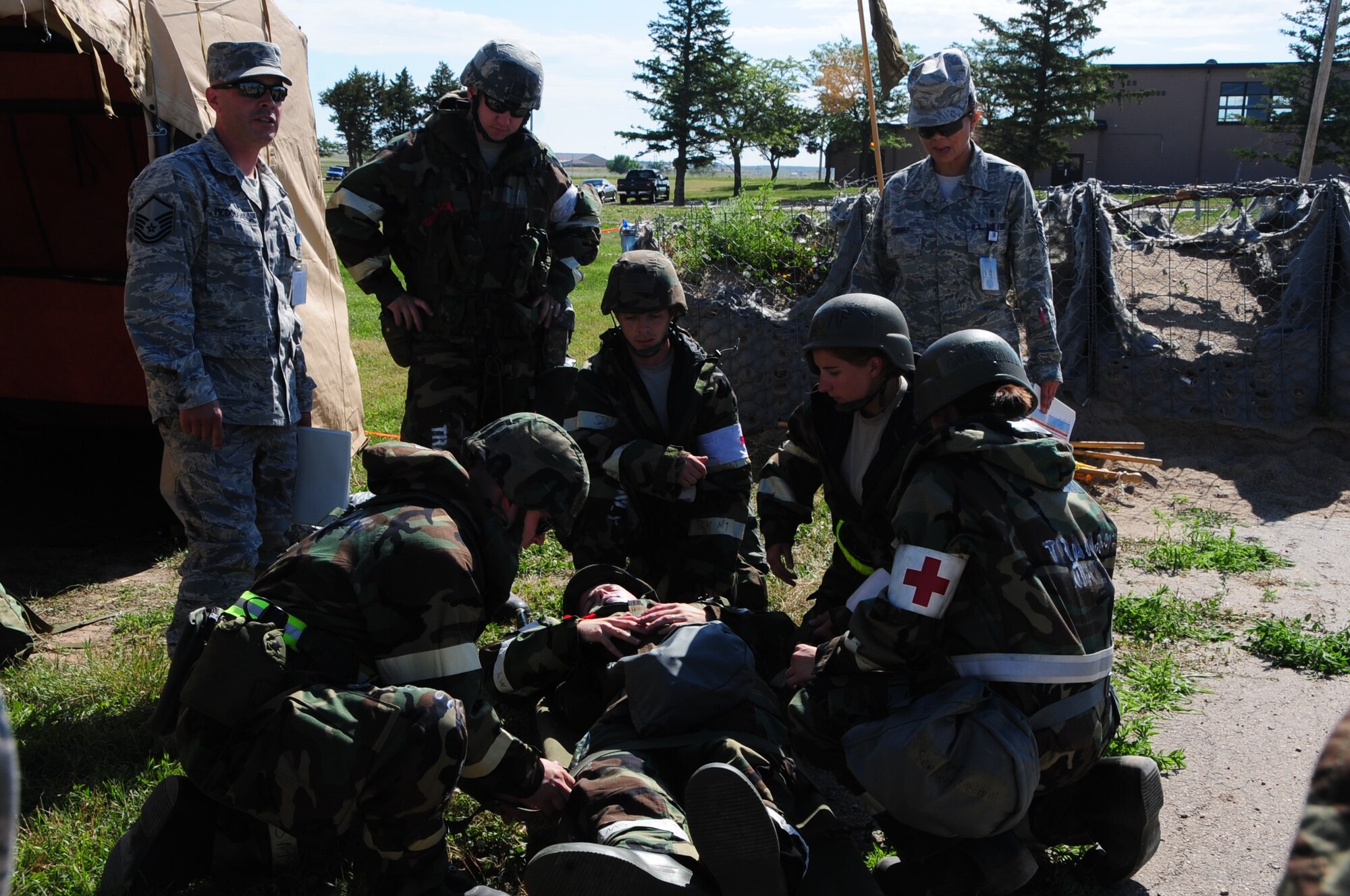 ELLSWORTH AIR FORCE BASE S.D. -- Airman 1st Class Corey Hook, 28th Bomb Wing photographer, lies on the ground with a simulated open abdominal wound, while Airmen from the 28th Medical Operations Squadron practice self-aid buddy care during a phase II operational readiness exercise, July 20.  The phase II ORE tests Airmen in a simulated deployed environment. (U.S. Air Force photo/Airman 1st Class Anthony Sanchelli)