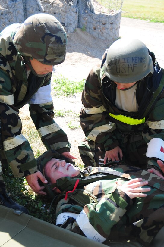 ELLSWORTH AIR FORCE BASE S.D. -- (Bottom to top) Airman 1st Class Corey Hook, 28th Bomb Wing photographer, lays on the ground with a simulated open abdominal wound while Staff Sgt Nathan Jongeling and Airman 1st Class Julie Kemps, 28th Medical Operations Squadron medical technicians complete self-aid buddy care, during a phase II operational readiness exercise, July 20.  The phase II ORE tests Airmen on their self-aid buddy care techniques and response time. (U.S. Air Force photo/Airman 1st Class Anthony Sanchelli)