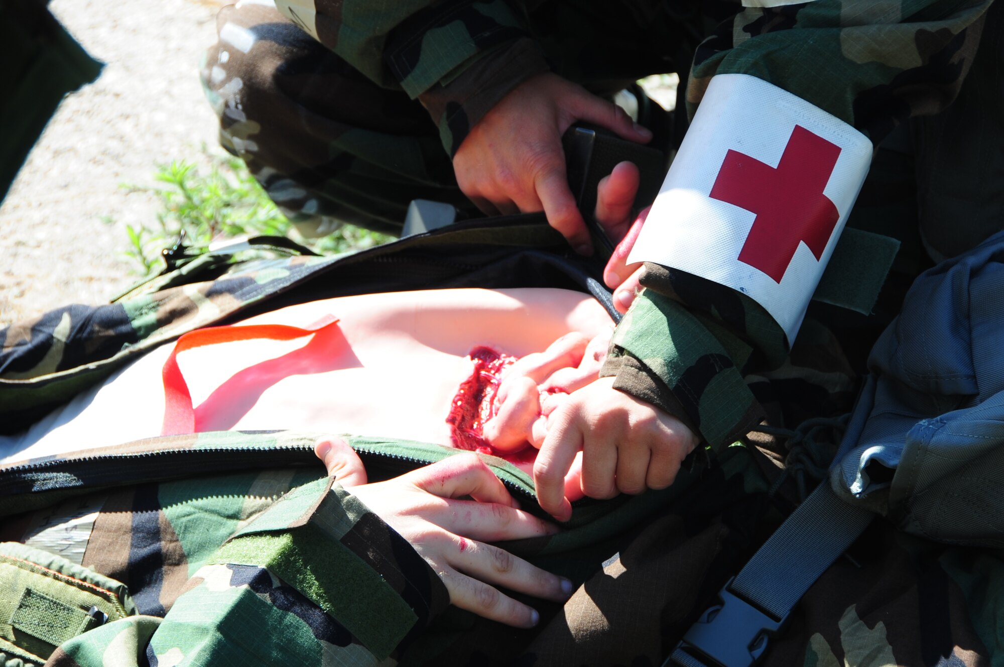 ELLSWORTH AIR FORCE BASE S.D. -- Airman 1st Class Corey Hook, 28th Bomb Wing photographer, lays on the ground with a simulated open abdominal wound during a phase II operational readiness exercise, July 20.  Treatment of an open abdominal wound falls under self-aid buddy care, which Airmen practice during the phase II ORE. (U.S. Air Force photo/Airman 1st Class Anthony Sanchelli)