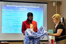 OFFUTT AIR FORCE BASE, Neb. - Billie Gaines, Chief of the Airmen and Family Readiness Center here, hands a blanket to Kim Spears, wife of 12th Air Force commander Lt. Gen. Glenn Spears July 14. The blanket was made by local Project Linus volunteers who create blankets and afghans for sick children. This was General Spears' first official visit to Offutt and he was briefed on mission capabilities, saw new buildings, met with young Airmen and hosted a wing-wide all call.  U.S. Air Force photo by Charles Haymond