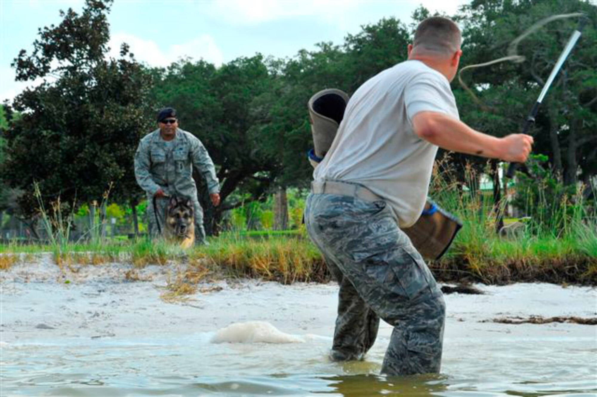 U.S. Air Force Staff Sgt. Roberto Matos stands his ground as he waits for Tech. Sgt. Pedro Guerrero to give Britta, a military working dog, the order to attack in a controlled water aggression exercise at Hurlburt Field, Fla., July 14, 2010. The goal of water aggression training is to allow the dogs to become more comfortable working in a variety of environments. Britta and Sergeants Matos and Guerrero are assigned to the 1st Special Operations Security Forces Squadron. (DoD photo by U.S. Air Force Senior Airman Sheila deVera/RELEASED)