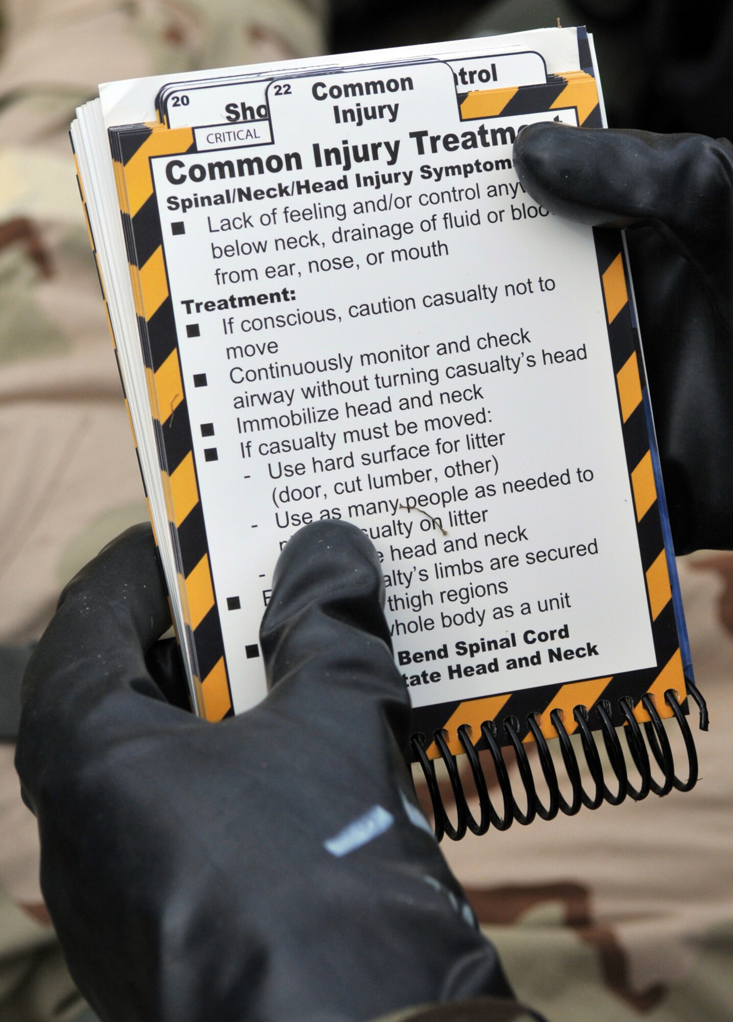 RAF MILDENHALL, England -- Tech. Sgt. Demarcus Anthony, 100th Logistics Readiness Squadron, consults his Airman's Manual while treating the simulated injuries of a teammate during exercise Quick Bank 10-06 July 20.  (U.S. Air Force photo/Staff Sgt. Austin M. May)