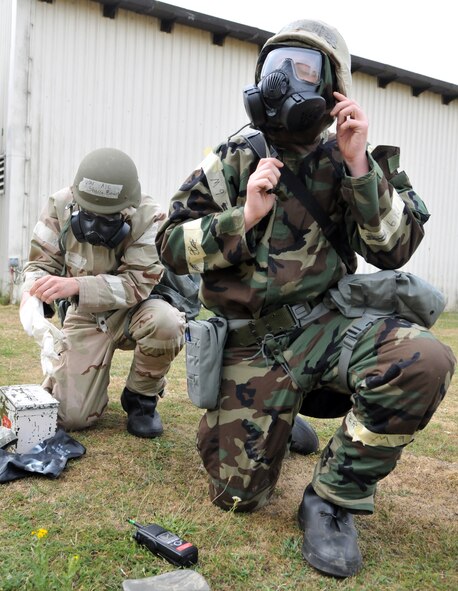 RAF MILDENHALL, England -- Senior Airman Neil Kohan and Airman 1st Class Shayn Bowen, 100th Logistics Readiness Squadron, don their chemical protection suits during a simulated attack July 20.  Both Airmen were participants in Quick Bank 10-06, a three-day exercise designed to test RAF Mildenhall's combat readiness.  (U.S. Air Force photo/Staff Sgt. Austin M. May)