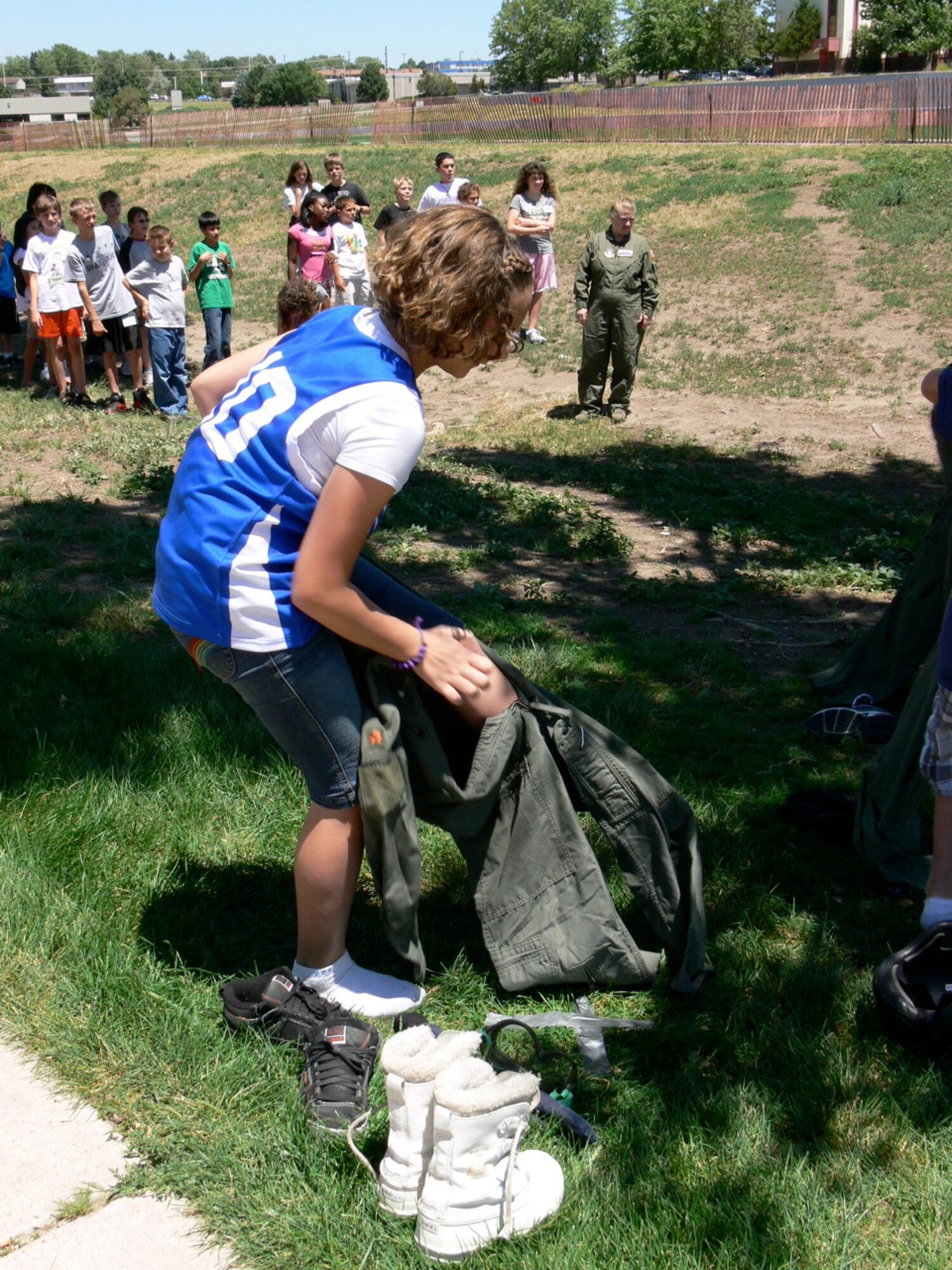Emily Boyce, 12, races to put on a “space suit,” consisting of boots and rubber gloves, to simulate wearing a space suit. Children in the “Federation of Galaxy Explorers, Moon Base One Camp,” at Jack Swigert Aerospace Academy, a Peterson Air Force Base feeder school, held a relay race where, once clad in their “space suits,” stacked building blocks to see which team could come up with the best design. (U.S. Air Force photo/Monica Mendoza)