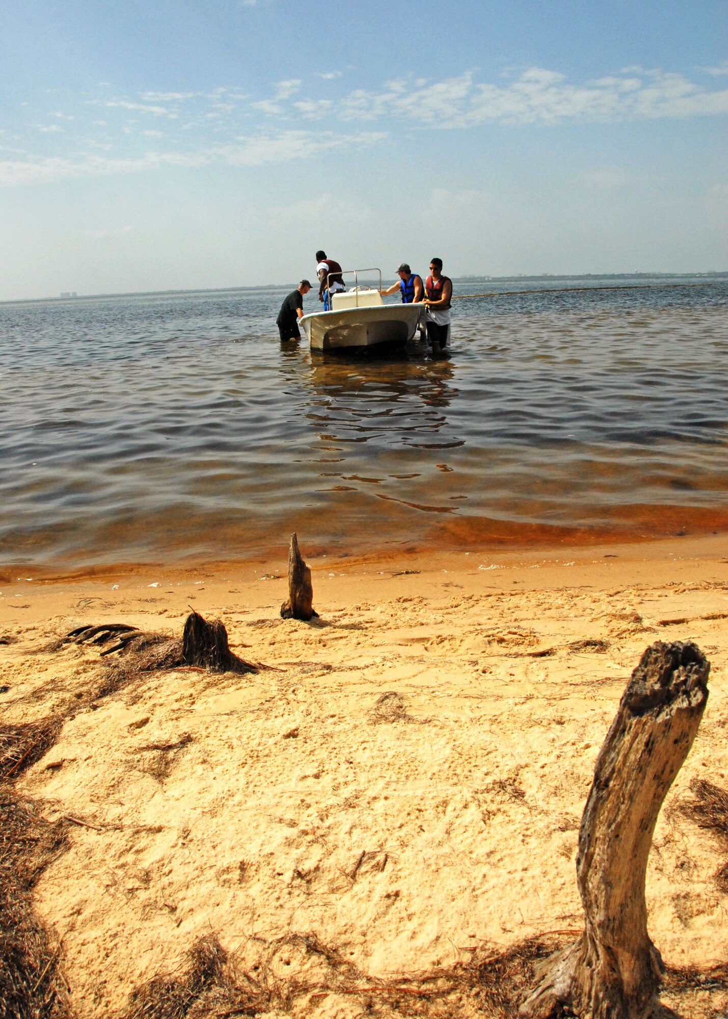 Volunteers arrive at the Eglin Air Force Base, Fla., shoreline towing 300 feet of boom to be installed in front of an inlet July 14.  Boom is an oil containment device used to trap oil in the water so it can be collected before reaching the shore.  Approximately 2,000 feet of booms have been installed around Eglin waterways.  (U.S. Air Force photo/Samuel King Jr.)