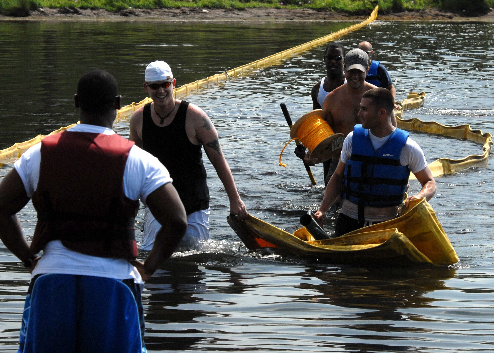 Volunteers return from the other bank after installing a boom across an inlet along the Eglin Air Force Base, Fla., shoreline.  Boom is an oil containment device used to trap oil in the water so it can be collected before reaching the shore.  Approximately 2,000 feet of booms have been installed around Eglin waterways.  (U.S. Air Force photo/Samuel King Jr.)
