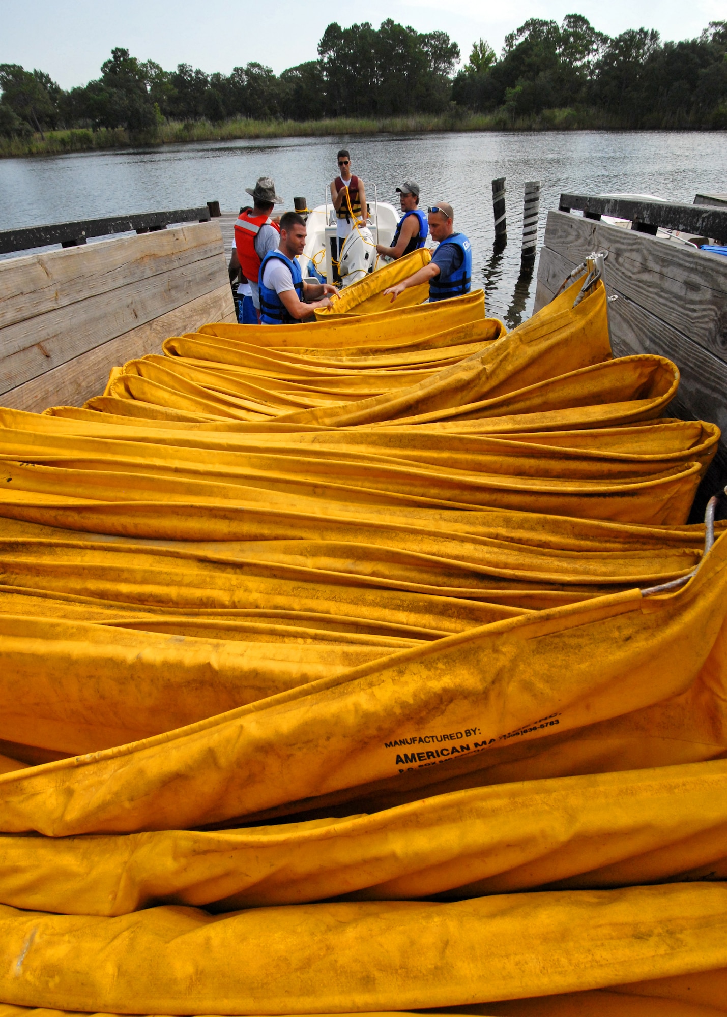 Volunteers begin pulling the 500 feet of oil boom to be installed from the trailer on Eglin Air Force Base, Fla., July 14.  Boom is an oil containment device used to trap oil in the water so it can be collected before reaching the shore.  Approximately 2,000 feet of booms have been installed around Eglin waterways.  (U.S. Air Force photo/Samuel King Jr.)  