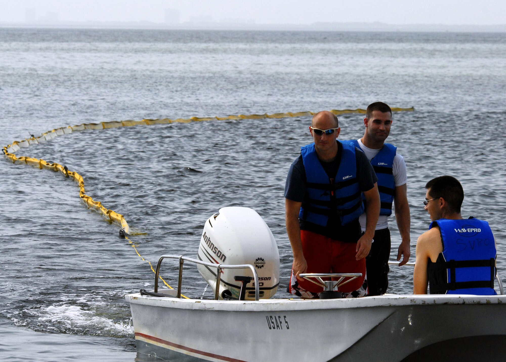 Volunteers bring the towed oil boom into shore prior to installing it along one of Eglin Air Force Base’s many shorelines July 14.  500 feet of boom was installed on that day.  Boom is an oil containment device used to trap oil in the water so it can be collected before reaching the shore.  Approximately 2,000 feet of booms have been installed around Eglin waterways.  (U.S. Air Force photo/Samuel King Jr.)  