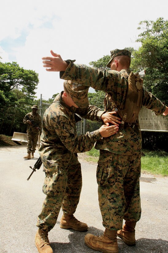 Lance Cpl. Steven A. Root, a combat engineer with 9th Engineer Support Battalion, 3rd Marine Logistics Group, III Marine Expeditionary Force, searches a mock-injured victim for weapons before letting him see medical personnel at an entry control point during Alert Contingency Marine Air Ground Task Force Exercise 2010 in the Central Training Area July 22.