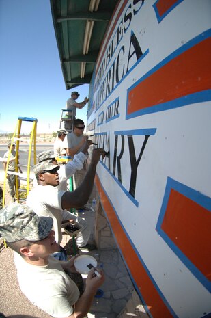 Airmen from the 372nd Training Squadron, Detachment 13, work as a team to repaint the flag sign in front of Davis Concrete Construction on Nellis Boulevard June 30. The Airmen repainted the sign to get rid of graffiti, improve community relations and show respect and proper display of the flag. (U.S. Air Force photo by Airman 1st Class Cynthia A. Haughton)