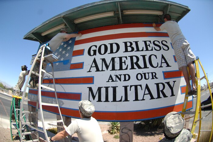 Airmen from the 372nd Training Squadron, Detachment 13, make preparations to repaint the flag sign in front of Davis Concrete Construction on Nellis Boulevard June 30. The Airmen repainted the sign to get rid of graffiti, improve community relations and show respect and proper display of the flag. (U.S. Air Force photo by Airman 1st Class Cynthia A. Haughton)