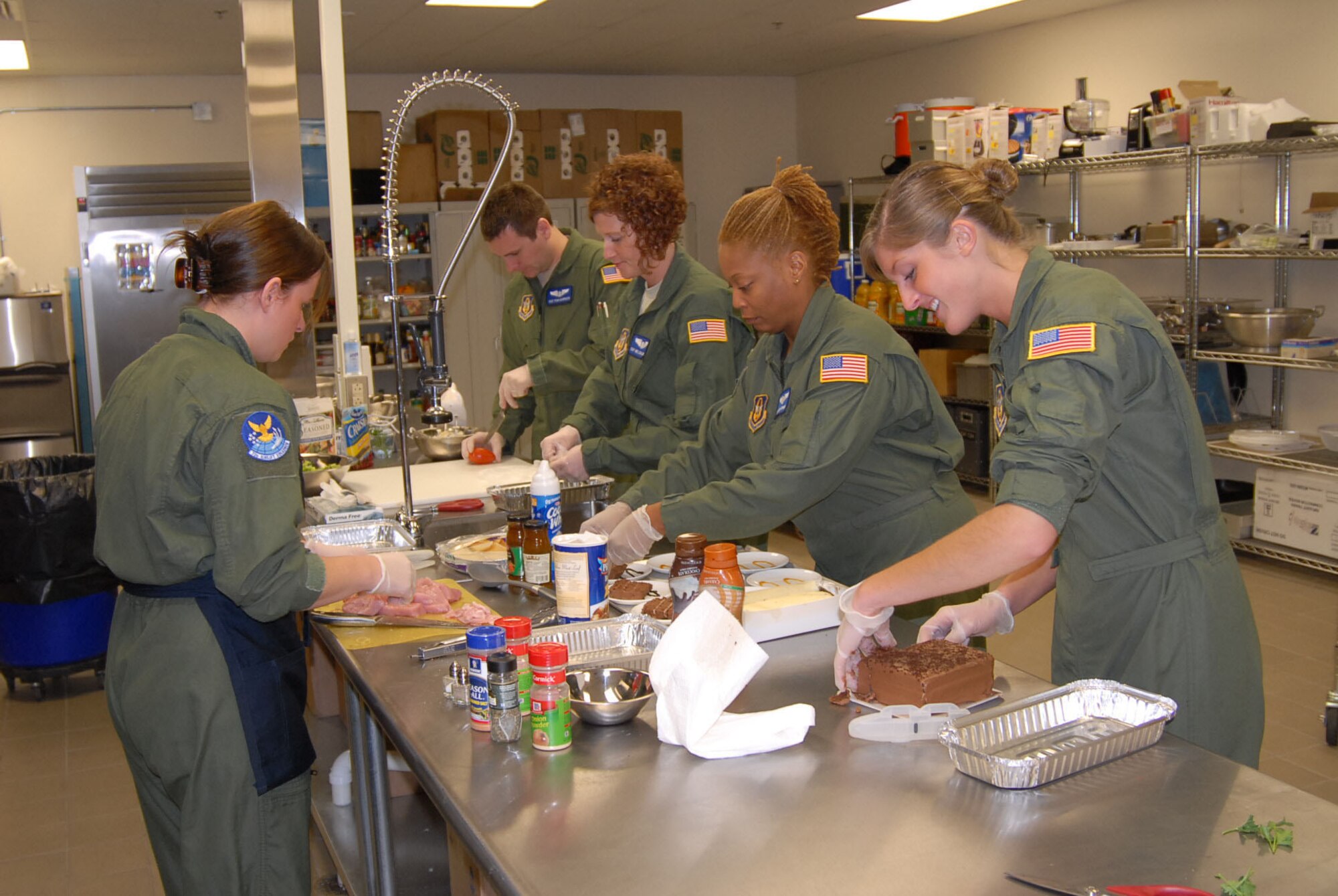 932nd Airlift Wing flight attendant crew members work on various pieces of a meal before taking off on a mission.  They are responsible for going to pick out ingredients and make an entire meal properly for leaders on distinguished visitor flights. (U.S. Air Force photo/Maj. Stan Paregien)