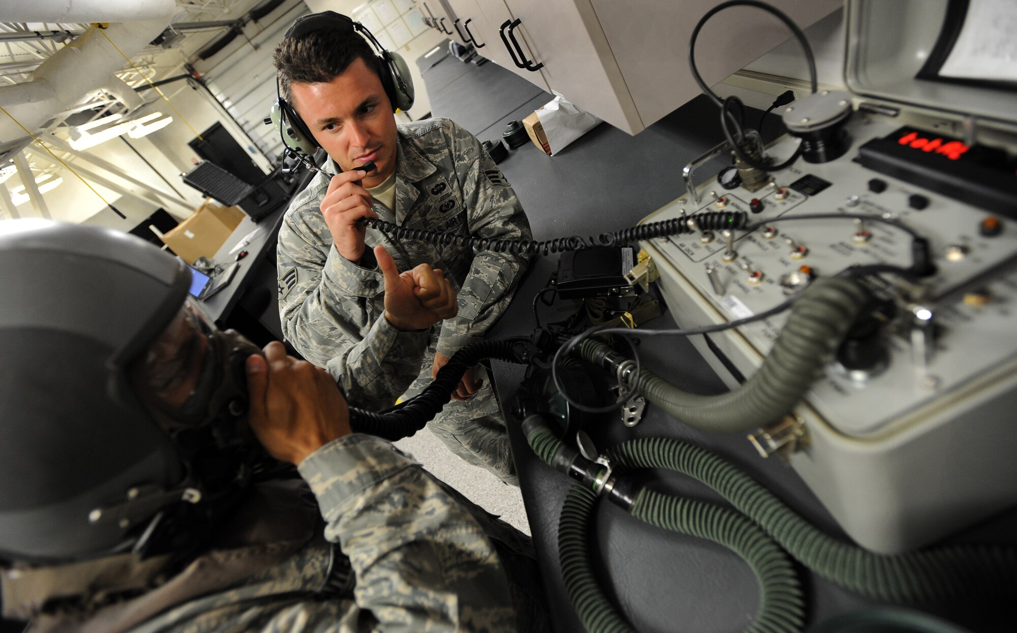 Airman 1st Class Frederick Gutierrez, 22nd Operations Support Squadron aircrew flight equipment apprentice, gives a thumbs up to Senior Airman Jeff Short, 22nd Operations Support Squadron aircrew flight equipment journeyman, to indicate a positive oxygen mask test July 20, 2010, McConnell Air Force Base, Kan. Aircrew flight equipment Airmen maintain and repair aircrew eye, respiratory and protective systems annually. The Airmen inspect more than 400 helmets each year. (U.S. Air Force photo/Senior Airman Courtney Witt)