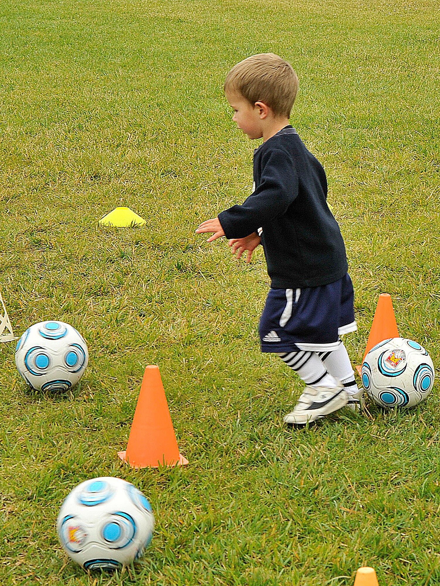 VANDNEBERG AIR FORCE BASE, Calif.--Ben Fernengel, son of Capt. Christopher Fernengel, of the 14th Air Force, tries to take down aliens (orange cones) by kicking their "laser" soccer ball during soccer camp here, Tuesday, July 20, 2010. European coaches with Challenge Sports incorporate games such as Alien Attack with basic soccer skills to keep children, ages three to four, interested in learning to play the game of soccer. (U.S. Air Force Photo/Senior Airman Stephanie Longoria)