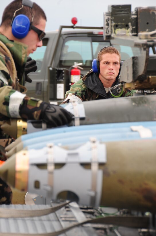 ELLSWORTH AIR FORCE BASE S.D. -- (Left to right) Airman 1st Class Alejandro Sanchez, 28th Munitions Squadron weapons loader, straps a guided bomb unit-38 to a trailer, while Staff Sgt. Matthew Egler, 28 MUNS weapons loader, drives a munitions handling unit during a phase II operational readiness exercise, July 21. During the phase II ORE, 28 MUNS Airmen are essential to achieving mission success in a simulated environment. (U.S. Air Force photo/Airman 1st Class Anthony Sanchelli)