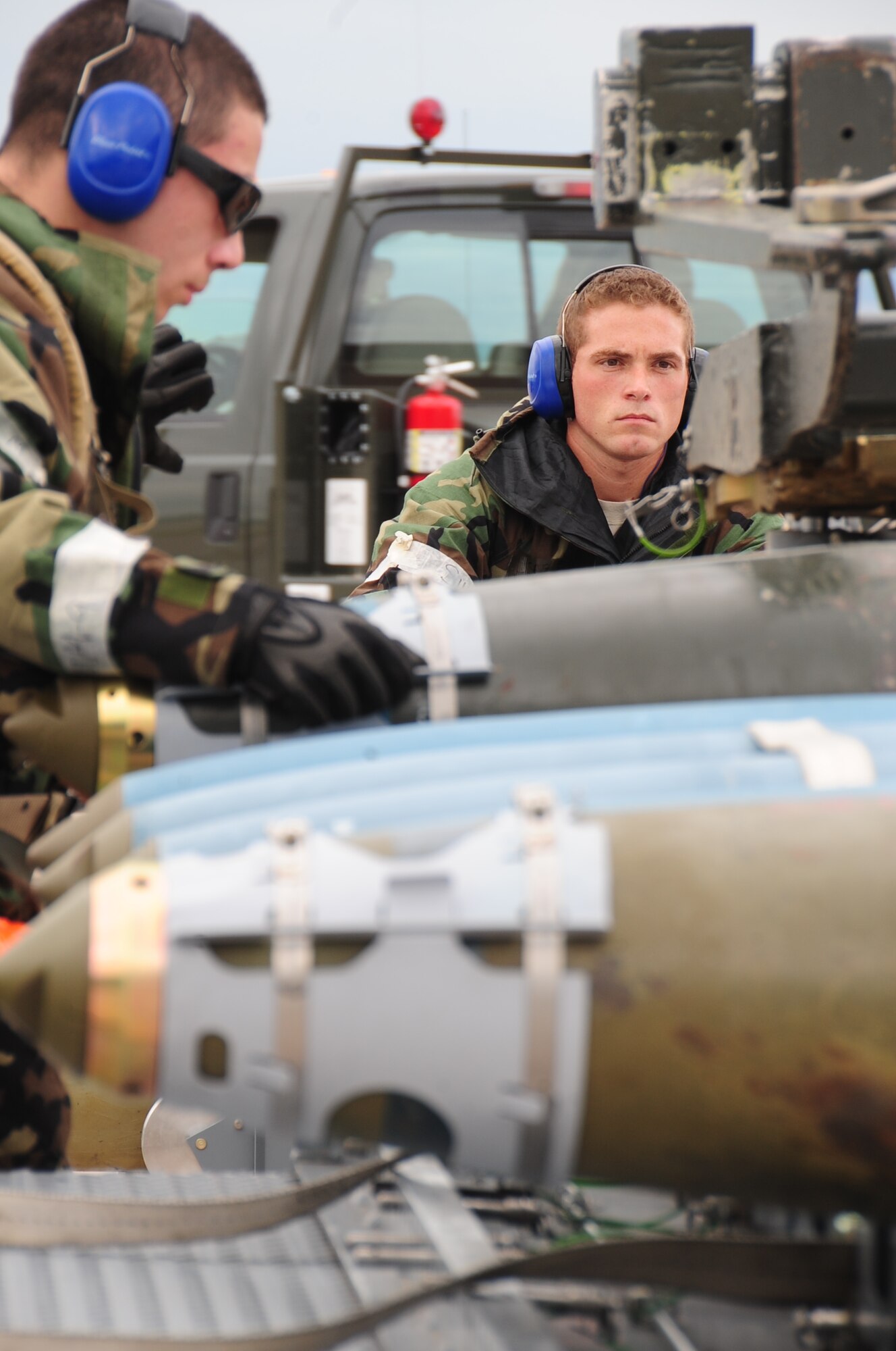 ELLSWORTH AIR FORCE BASE S.D. -- (Left to right) Airman 1st Class Alejandro Sanchez, 28th Munitions Squadron weapons loader, straps a guided bomb unit-38 to a trailer, while Staff Sgt. Matthew Egler, 28 MUNS weapons loader, drives a munitions handling unit during a phase II operational readiness exercise, July 21. During the phase II ORE, 28 MUNS Airmen are essential to achieving mission success in a simulated environment. (U.S. Air Force photo/Airman 1st Class Anthony Sanchelli)