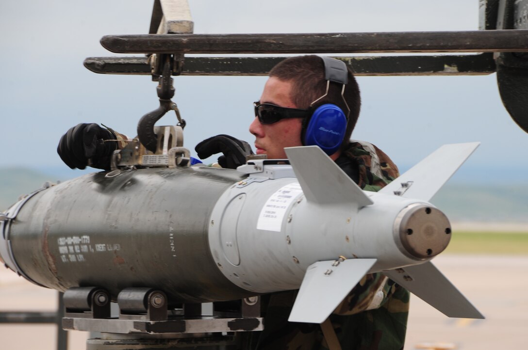 ELLSWORTH AIR FORCE BASE S.D. -- Airman 1st Class Alejandro Sanchez, 28th Munitions Squadron weapons loader, straps a guided bomb unit-38 to a munitions handling unit before it's loaded onto a B-1B Lancer during a phase II operational readiness exercise, July 21.  During the phase II ORE, Airmen must continue to perform their duties despite having to wear mission-oriented protective posture gear over the Airman battle uniform. (U.S. Air Force photo/Airman 1st Class Anthony Sanchelli)