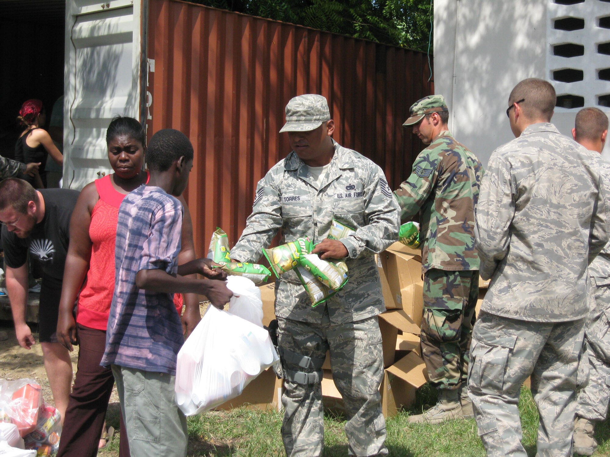 Technical Sergeant Juan Torres, 436th Logistic Readiness Squadron assistant non-commissioned officer in charge of vehicle management and analysis, passes out food to children at a Haitian orphanage during his temporary duty assignment where he was attached to the 24th Air Expeditionary Group as fleet manager.  Sergeant Torres was awarded an Air Force Achievement medal as well as a coin from Admiral Mike Mullen, Chairman Joint Chiefs of Staff.  (Courtesy photo)