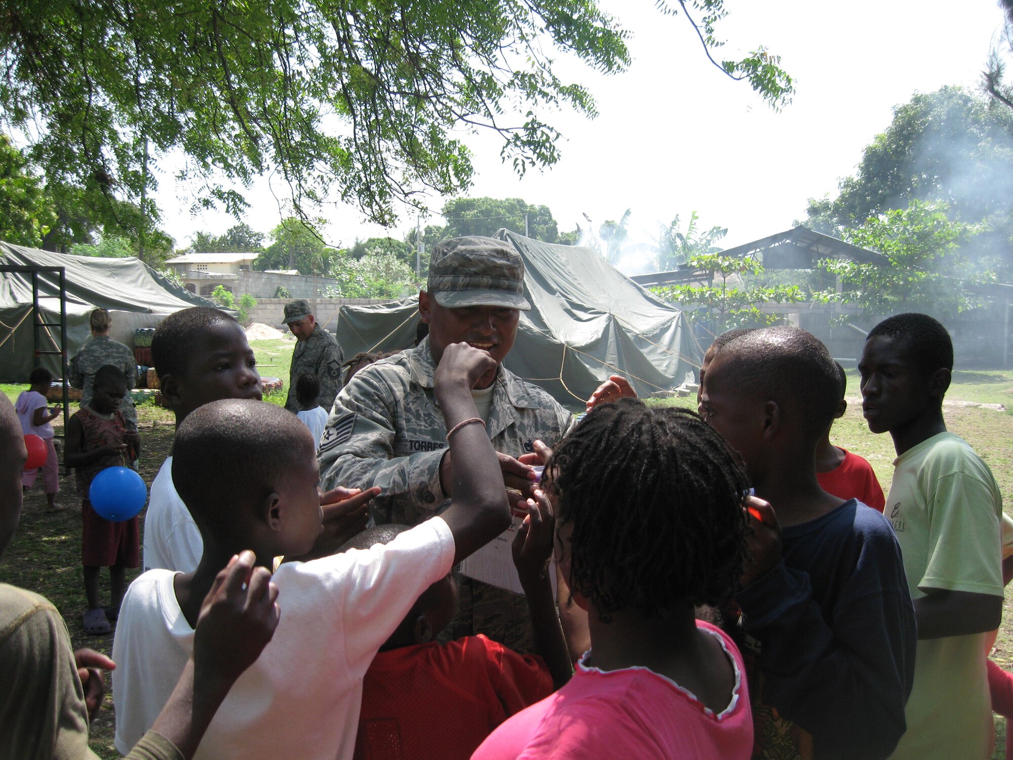 Technical Sergeant Juan Torres, 436th Logistic Readiness Squadron assistant non-commissioned officer in charge of vehicle management and analysis, hands out candy to Haitian children during his temporary duty assignment where he was attached to the 24th Air Expeditionary Group as fleet manager.  Sergeant Torres volunteered much of his free time assisting Haitian orphans.  (Courtesy photo)