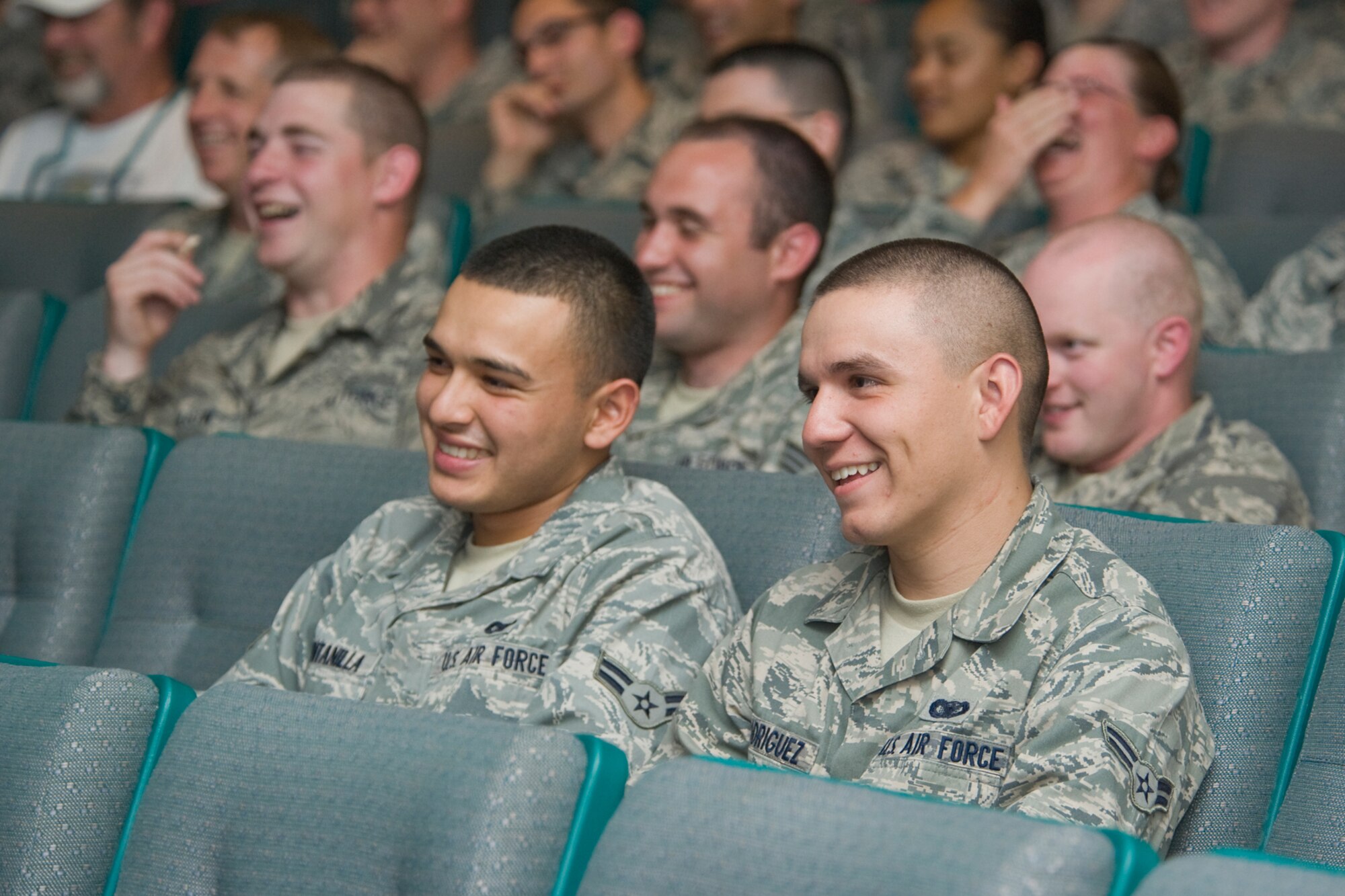 Airmen 1st Class Jerry Quintanilla and Michael Rodriguez, 341st Security Forces Squadron members, laugh at a joke told by comedian Bernie McGrenahan during an alcohol and drug prevention program at the base theater July 16. 