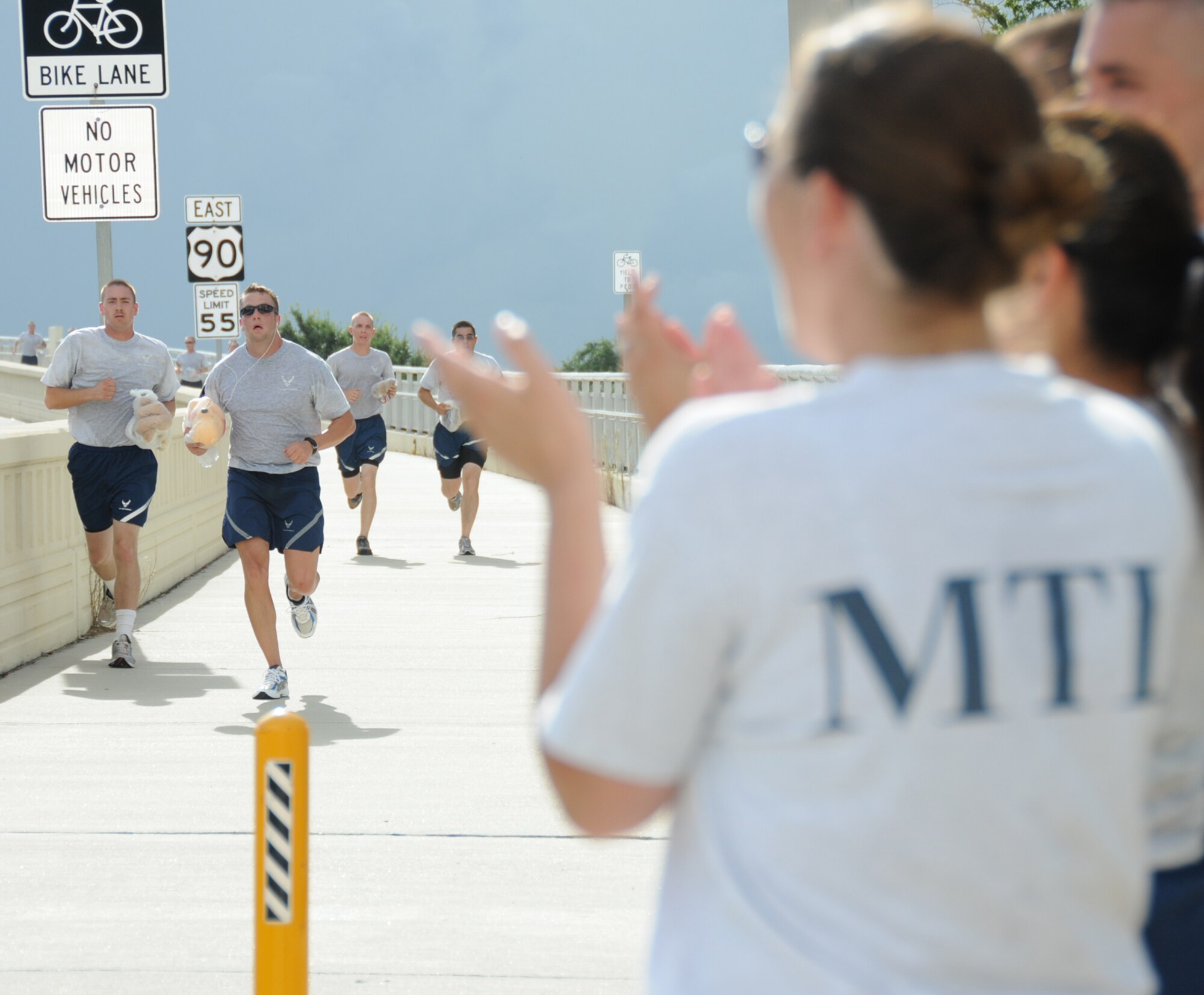 From left, Airman 1st Class William Johnson, 332nd TRS, and Master Sgt. Justin Christman, 338th TRS, are cheered on by Tech. Sgt.  Julie Hammond, an 81st Training Group military training leader, as they reach the finish line.  Participants included 160 students and 20 permanent party members from the 81st TRG.    (U.S. Air Force photo by Kemberly Groue)
