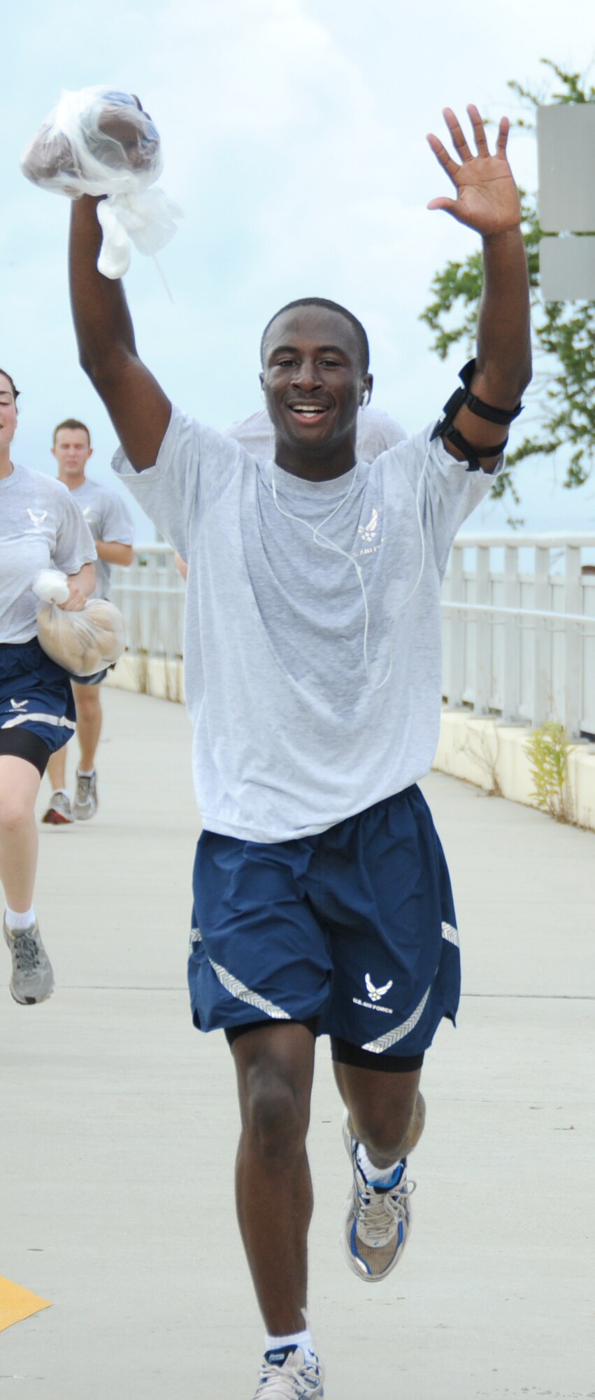 Airman 1st Class Stanley Wesley, 332nd TRS, lifts his arms and a teddy bear in triumph as he finishes the 3.2 mile run.   (U.S. Air Force photo by Kemberly Groue)
