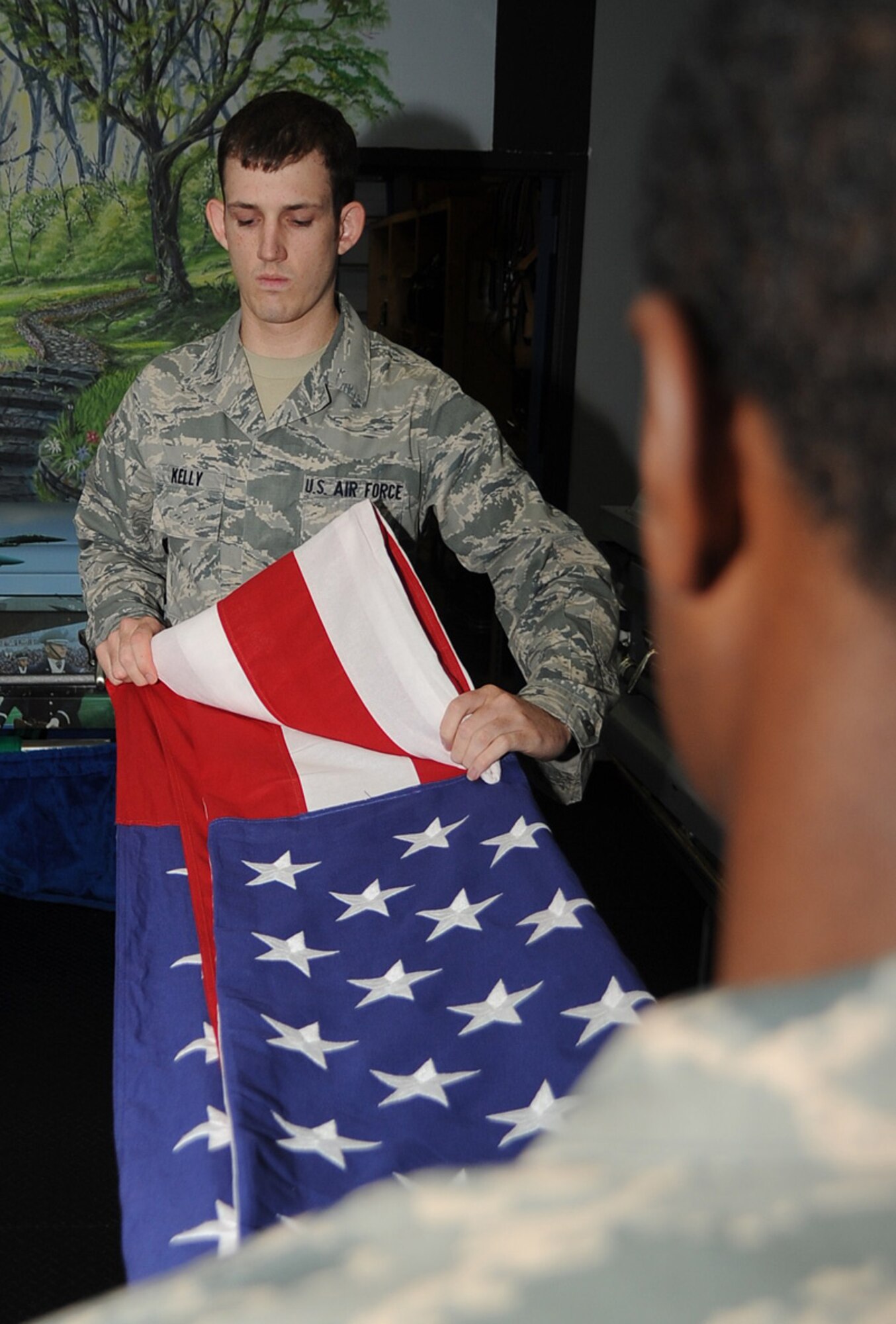 Airman 1st Class Steven Kelly, Joint Base McGuire-Dix-Lakehurst Honor Guard trainer, and Staff Sgt. Victor Fowler, 305th Maintenance Squadron, practice flag folding at the Honor Guard facility here Tuesday. The JB MDL Honor Guard provides ceremonial services to five different states within the Northeast region of the country. (U.S. Air Force photo/ Airman 1st Class/ Bryan Swink)