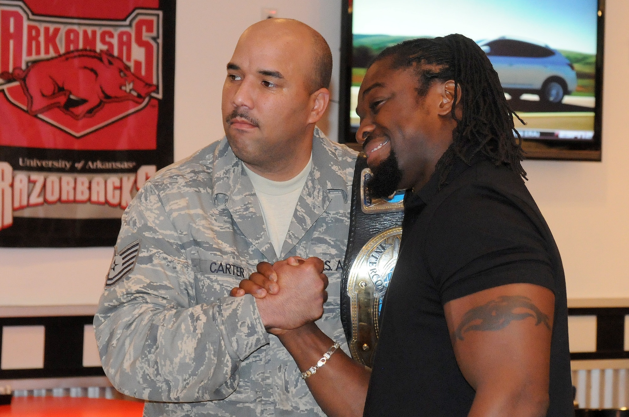 Tech. Sgt. Iberville Carter, a 19th Force Support Squadron production manager, poses for a photo with World Wrestling Entertainment Intercontinental Champion Kofi Kingston July 20 during a visit at Hangar 1080 on base. WWE Superstars entertained Arkansas professional wrestling fans with an event at the local arena in Little Rock recently. (U.S. Air Force photo by Senior Airman Steele C. G. Britton)