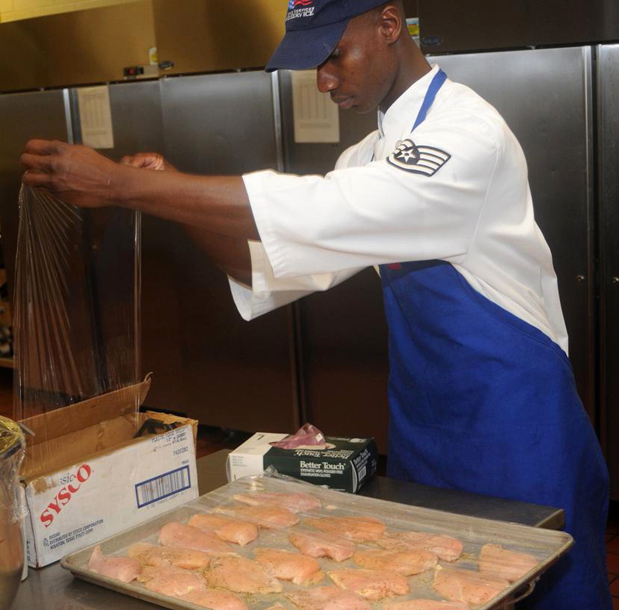 Staff Sgt. John Charles, 512th Memorial Affairs Squadron, Dover Air Force Base, Del., food prep specialist, preserves uncooked chicken for later use at Patterson Dining Facility kitchen here June 6. Sergeant Charles said he likes his job and enjoys working in the dining facility. (U.S. Air Force photo/Senior Airman Bhawan P. Singh)