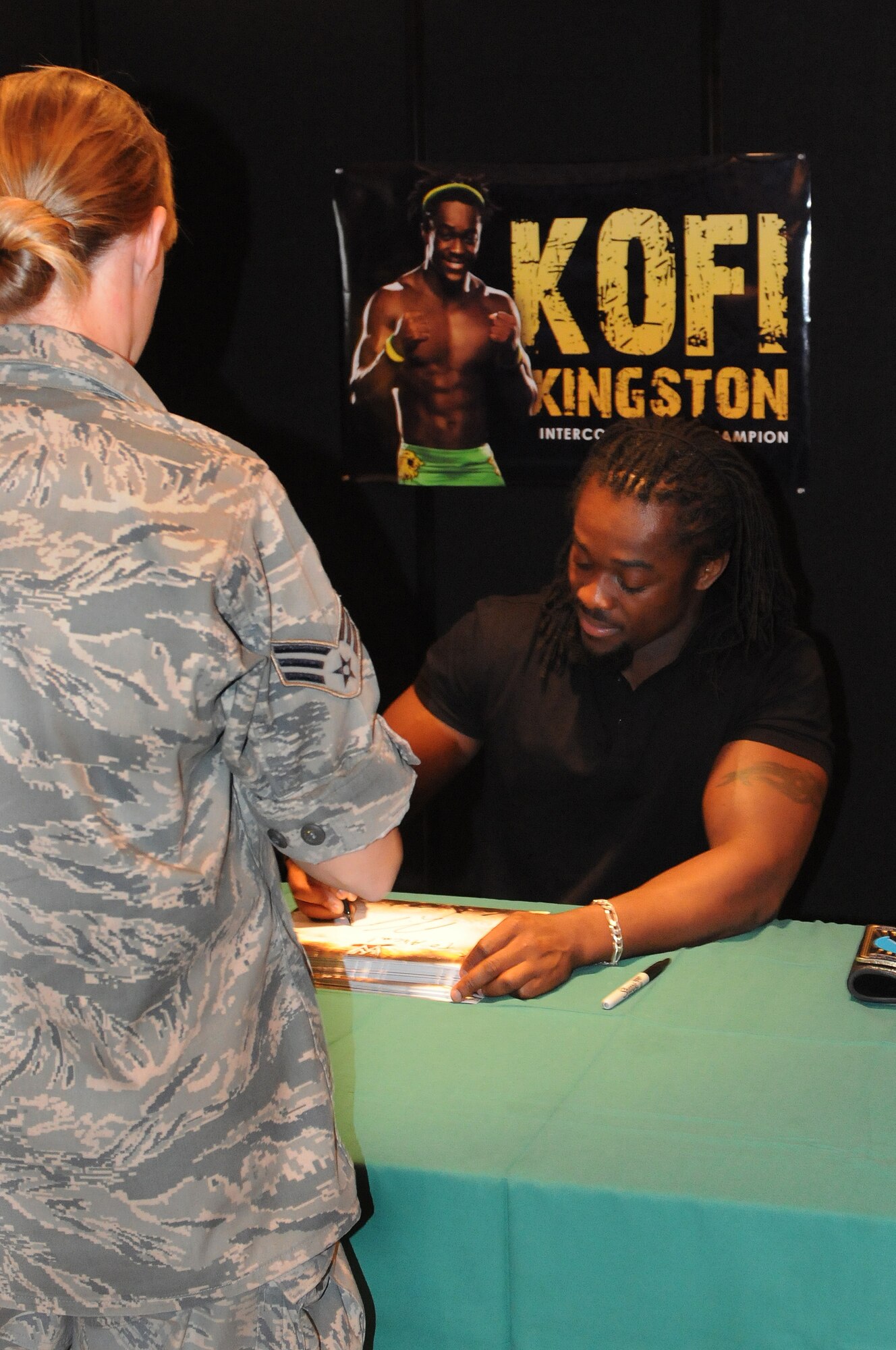 World Wrestling Entertainment Intercontinental Champion Kofi Kingston signs an autograph July 20 for Senior Airman Alicia Reese, 19th Component Maintenance Squadron, at Hangar 1080. Kofi Kingston and fellow 'Smackdown!' Superstars visited Little Rock, Ark., for a live performance at the local arena. (U.S. Air Force photo by Senior Airman Steele C. G. Britton)