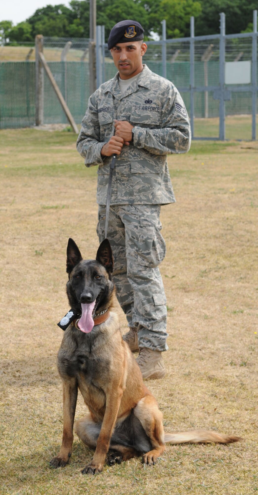 RAF MILDENHALL, England -- Military Working Dog Vvonya, shows off her official police badge as she poses with her handler Staff Sgt. Raymond McMahon, 100th Security Forces Squadron. Vvonya is the flight's first female Puppy Program dog. (U.S. Air Force photo/Karen Abeyasekere)