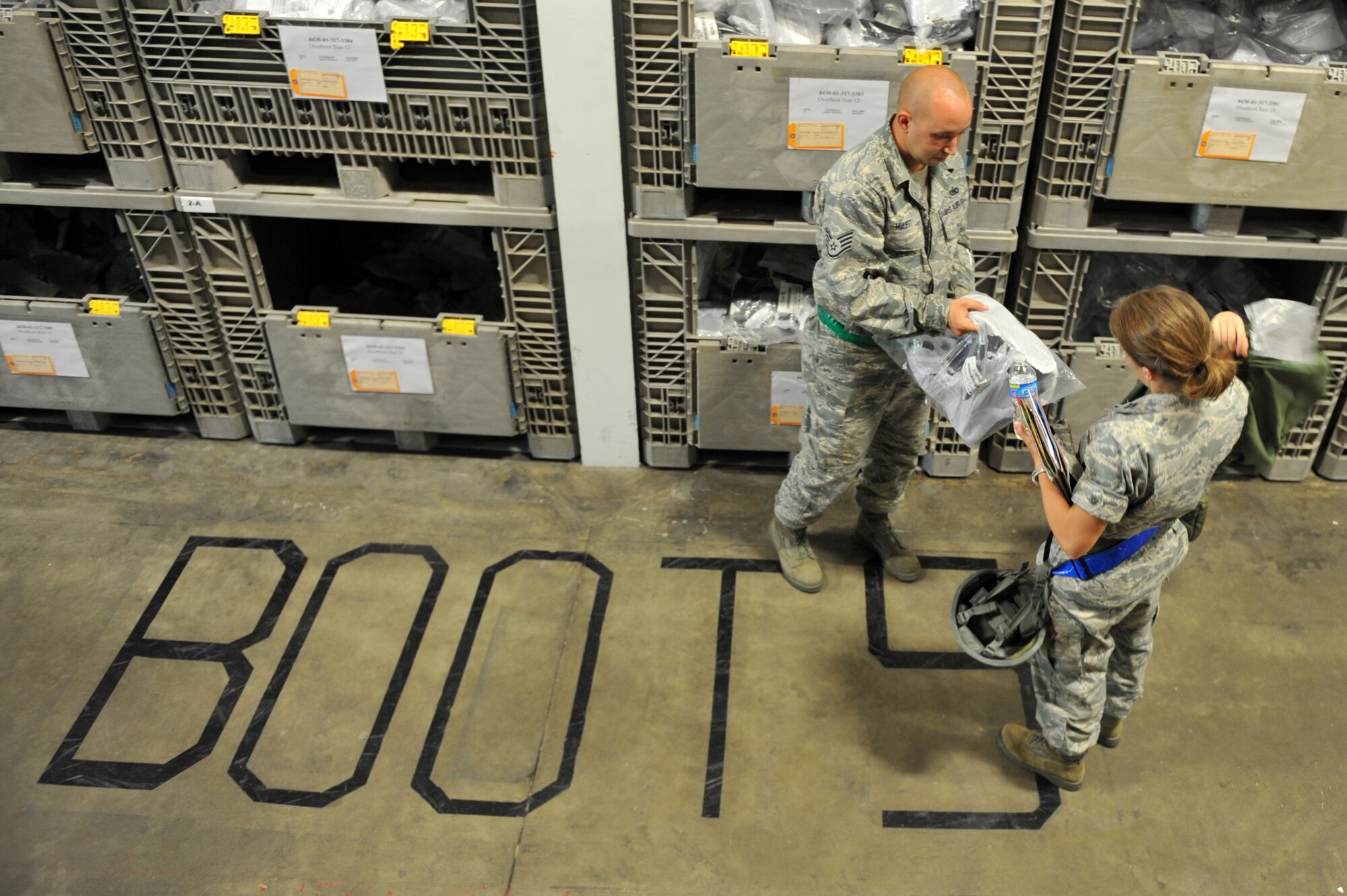 Staff Sgt. Justin Hulett, a 19th Logistics Readiness Squadron augmentee, issues chemical boots July 18 to an Airman at the passenger terminal mobility line. Airmen contributed efforts to the Little Rock Exercise outside of their career fields just as they would in real-world operations. (U.S. Air Force photo by Senior Airman Steele C. G. Britton)
