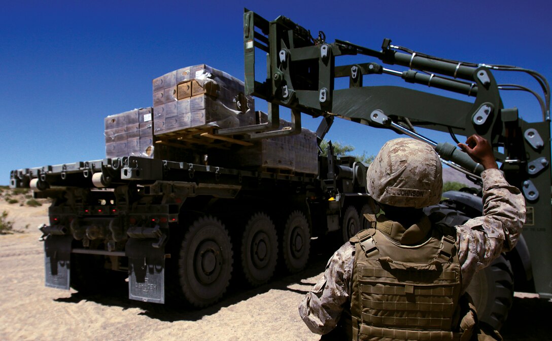 Sgt. Jimmie Johnson, logistics vehicle operator, 2nd platoon, Motor Transport Company A, CLB-3, 3rd Marine Logistics Group, III Marine Expeditionary Force, gives hand signals while guiding a heavy equipment movement vehicle July 23 at Marine Corps Air-Ground Combat Center, Twentynine Palms, Calif.