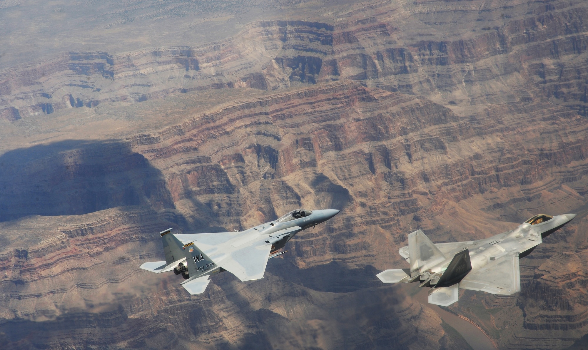 NELLIS AIR FORCE BASE, Nev.--An F-22A Raptor and F-15C Eagle from the U.S. Air Force Weapons School's 433rd Weapons Squadron fly in formation over the Grand Canyon July 16, 2010.  The 433rd WPS is the only Weapons School squadron that operates two different types of aircraft.  The Weapons School began in the late 1940s as the U.S. Air Force Gunnery School and teaches graduate-level instructor courses, providing the world's most advanced training in weapons and tactics employment. (U.S. Air Force photo by Master Sgt. Kevin J. Gruenwald)
