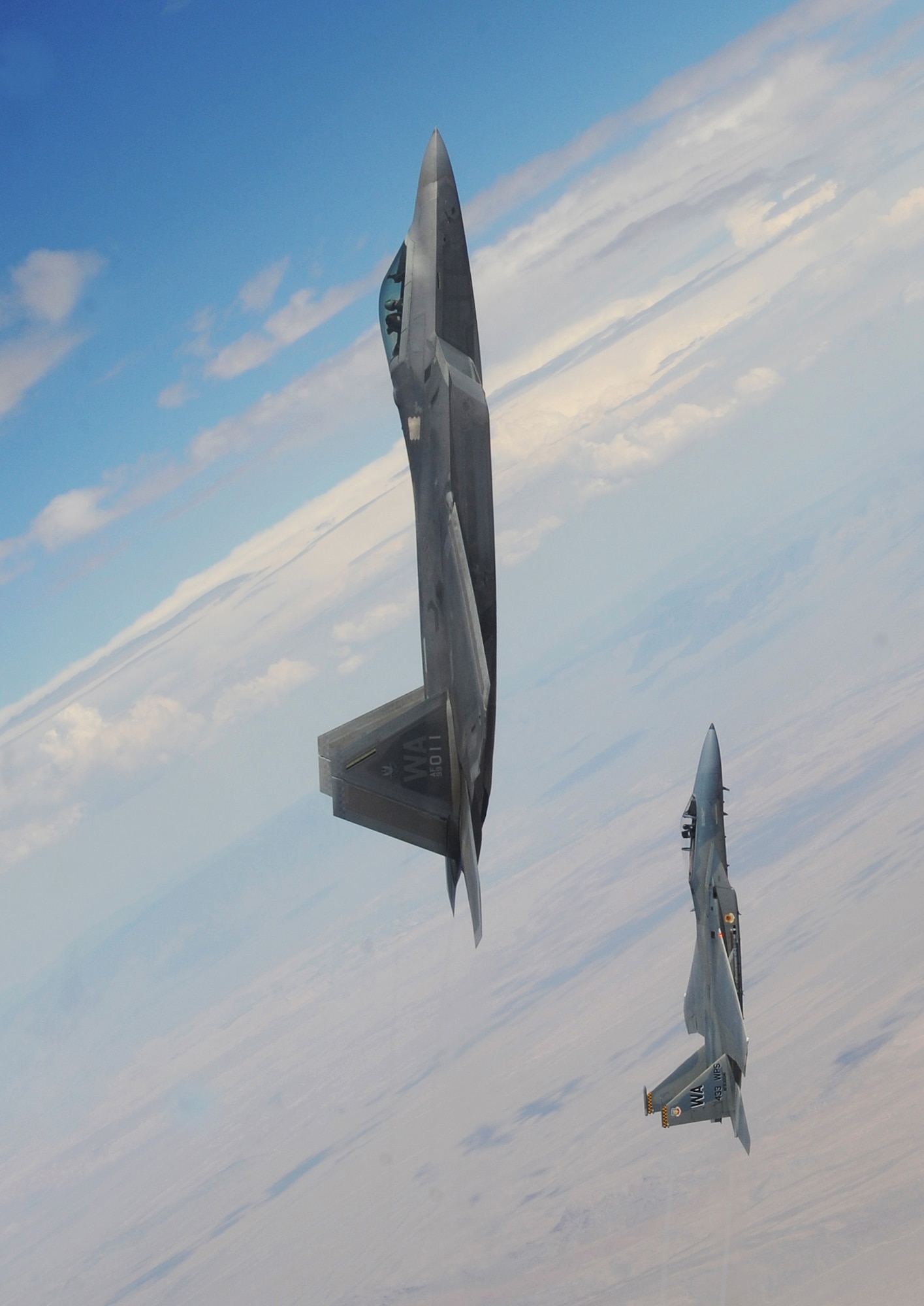 NELLIS AIR FORCE BASE, Nev.--An F-22A Raptor and F-15C Eagle from the U.S. Air Force Weapons School's 433rd Weapons Squadron pull into a vertical climb over the Nevada Test and Training Range July 16, 2010.  The NTTR is the U.S. Air Force’s premier military test and training facility with more than 12,000 square miles of airspace and 2.9 million acres of land. With 1,900 possible targets, realistic threat systems and the support of an opposing enemy force from Nellis Air Force Base, the NTTR provides the combat air force with a "peacetime battlefield" that cannot be replicated anywhere else in the world.  The Weapons School began in the late 1940s as the U.S. Air Force Gunnery School and teaches graduate-level instructor courses, providing the world's most advanced training in weapons and tactics employment. (U.S. Air Force photo by Master Sgt. Kevin J. Gruenwald)

